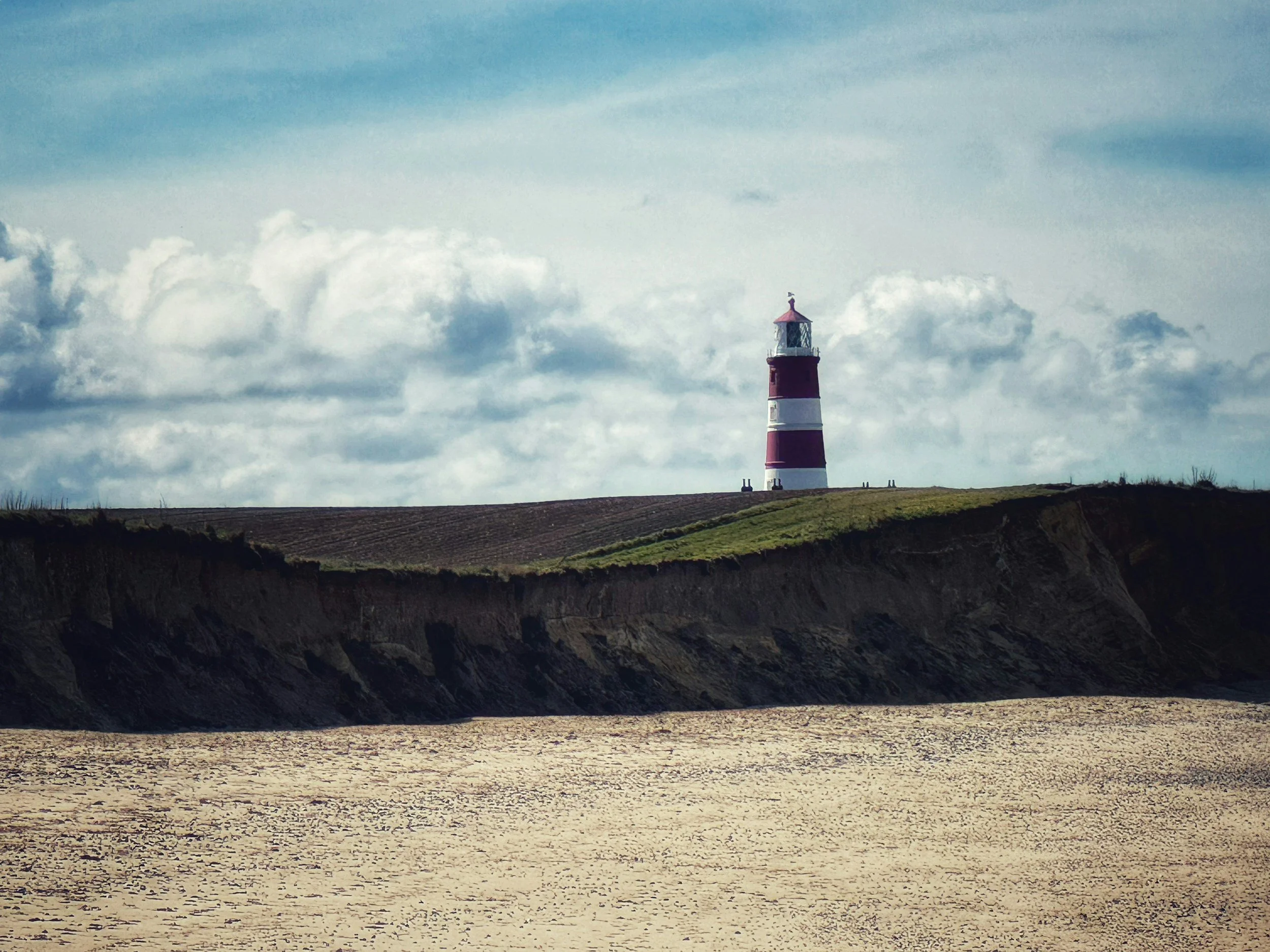 A lighthouse standing on the edge of the Norfolk cliffs