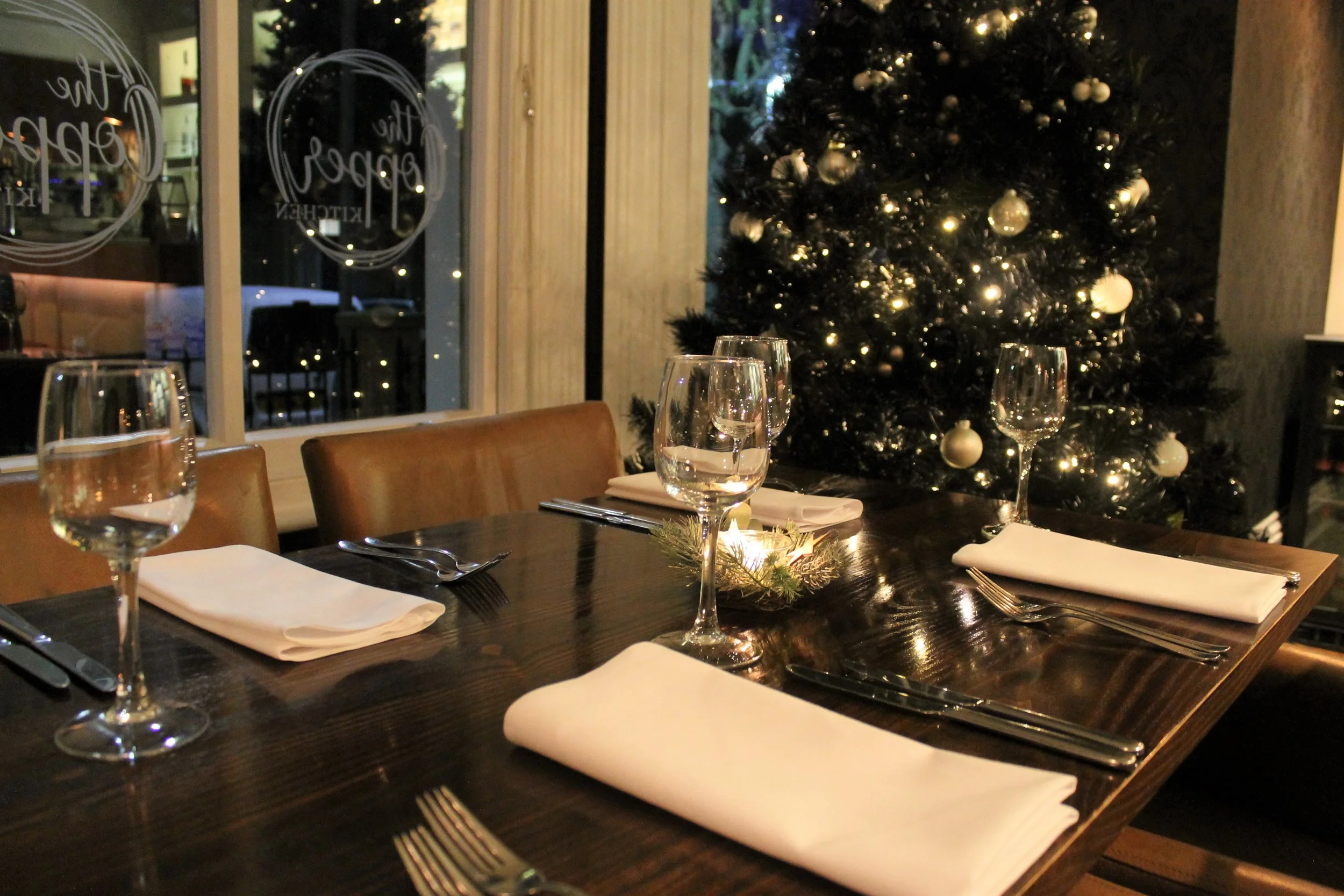 Christmas table setting in window at Great Yarmouth hotel with decorated tree, napkins, glassware