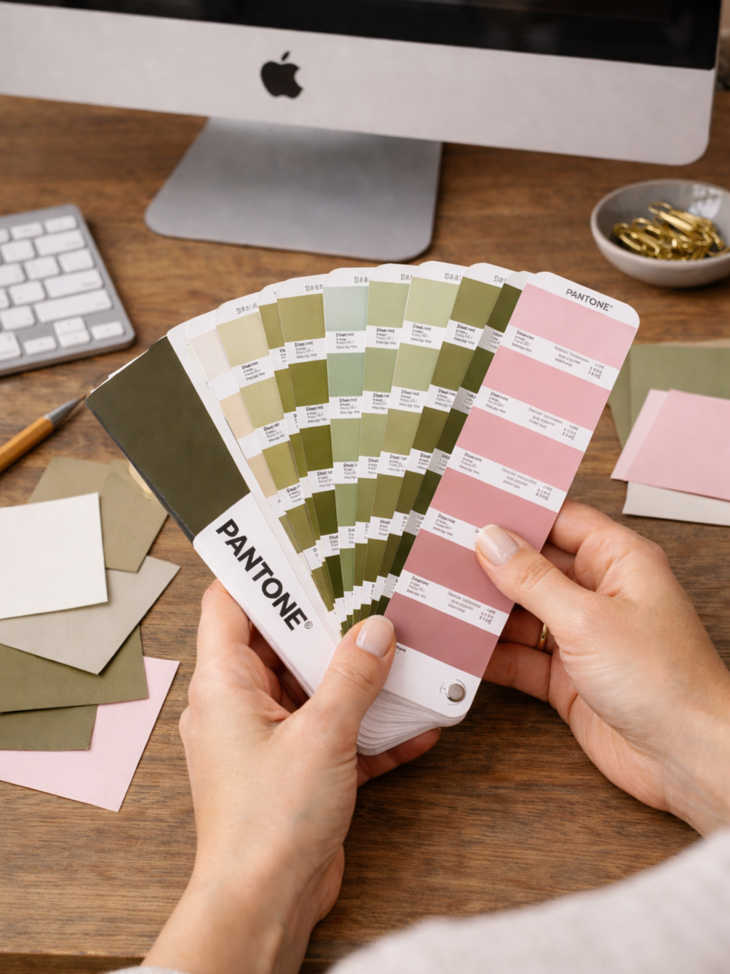 Wedding invitation designer looking through a Pantone color swatch book.