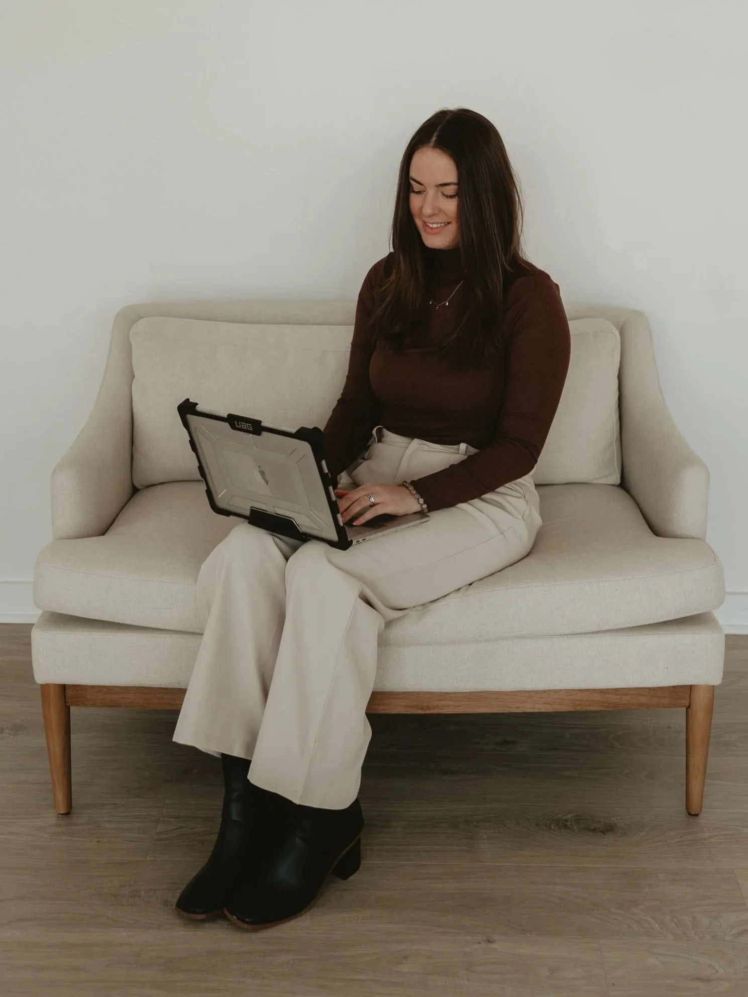 Wedding invitation designer sitting on an office couch looking at a laptop