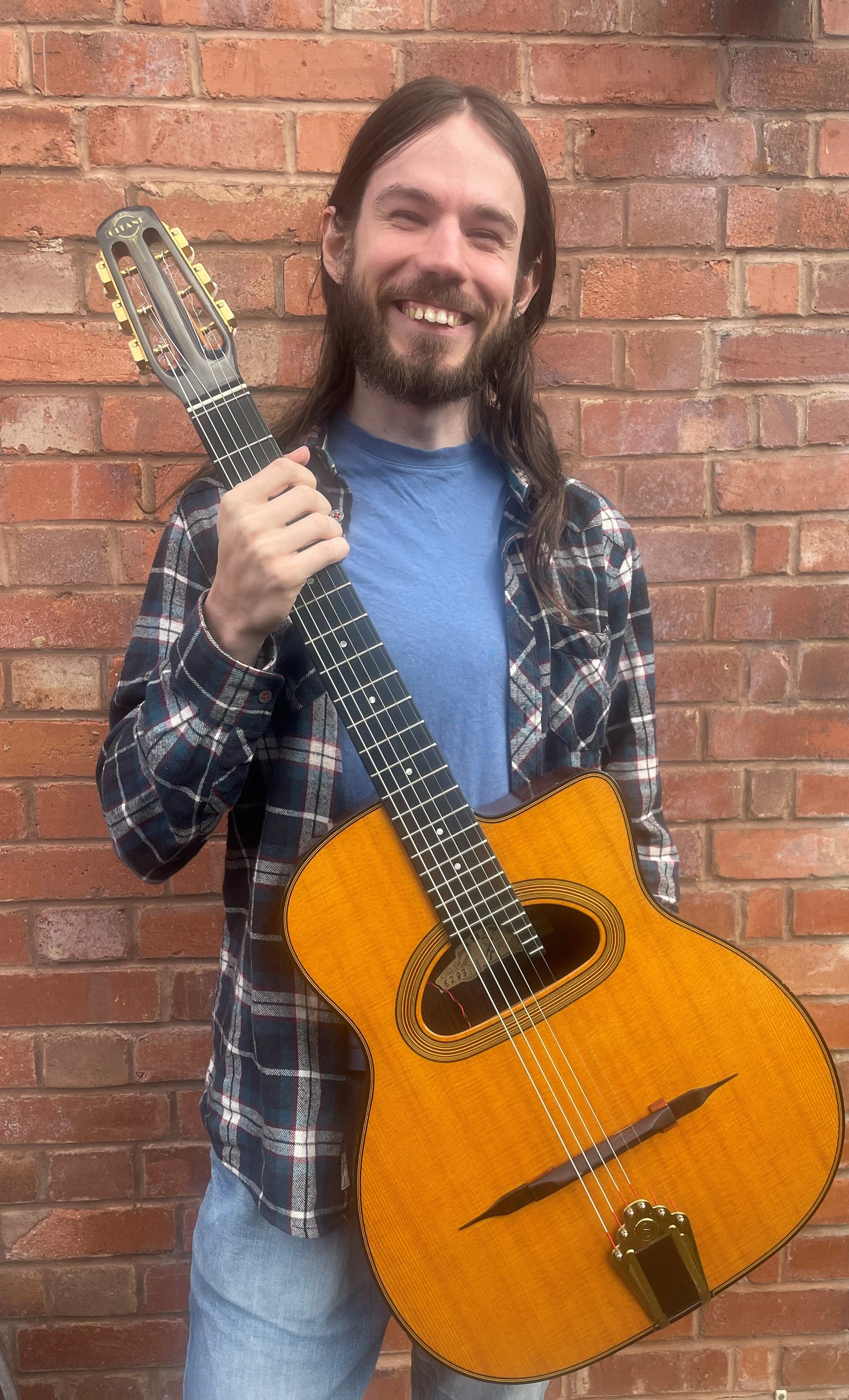 Guitar Tutor Matt Aaronson from Exeter, holding guitar and smiling