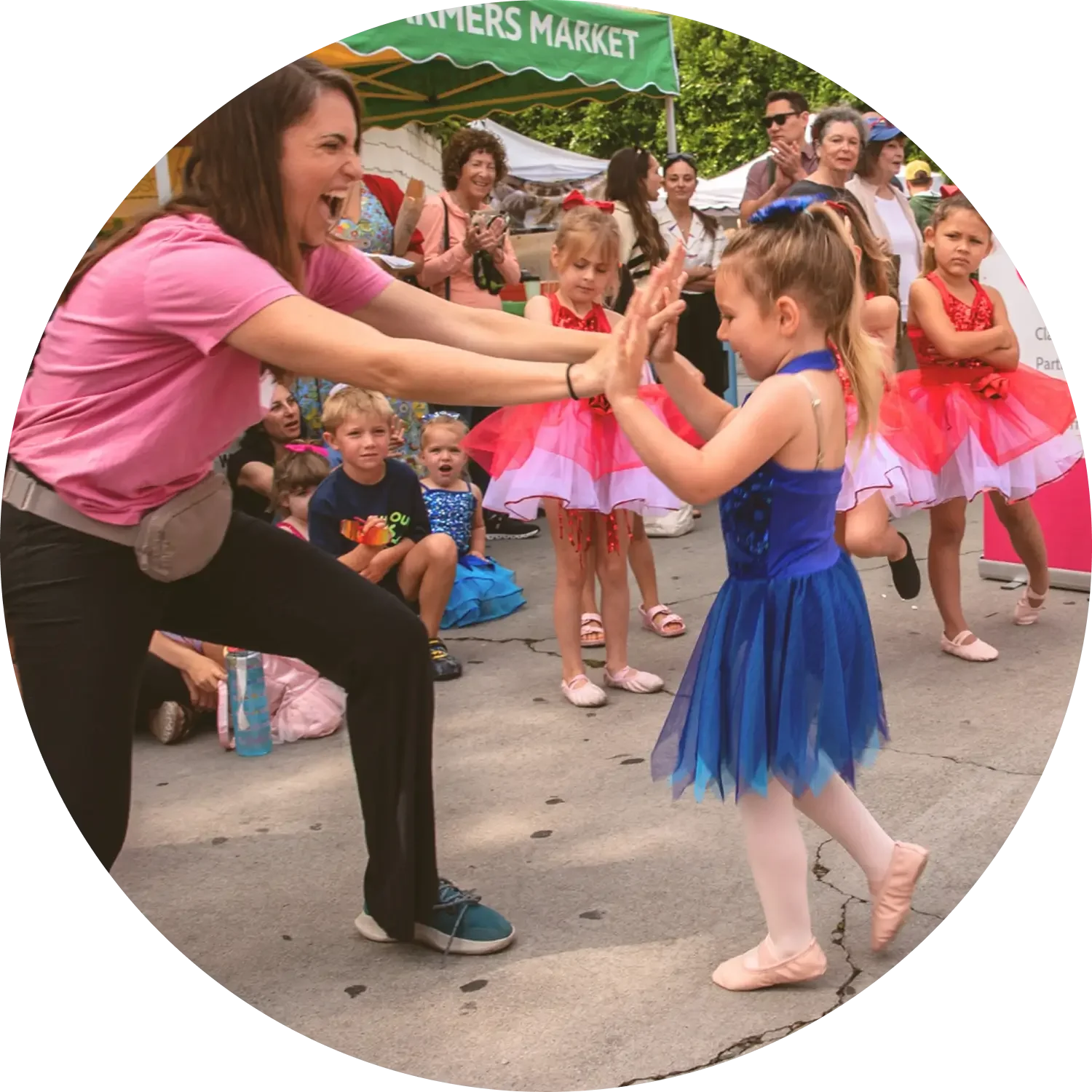 Miss Bethany of Dance with Miss Alice dancing with a young student at an outdoor performance.
