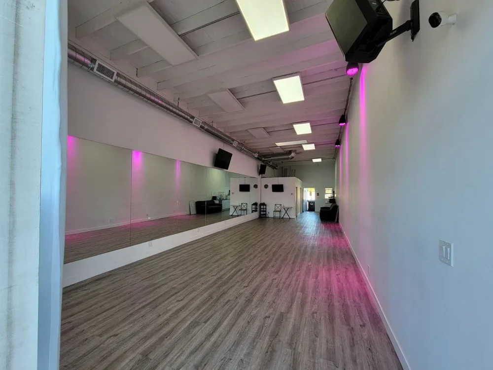 Dance with Miss Alice dance studio with wood floors, a mirrored wall, and pink lighting accents along the wall. Located in 11660 W Pico Blvd, Los Angeles.