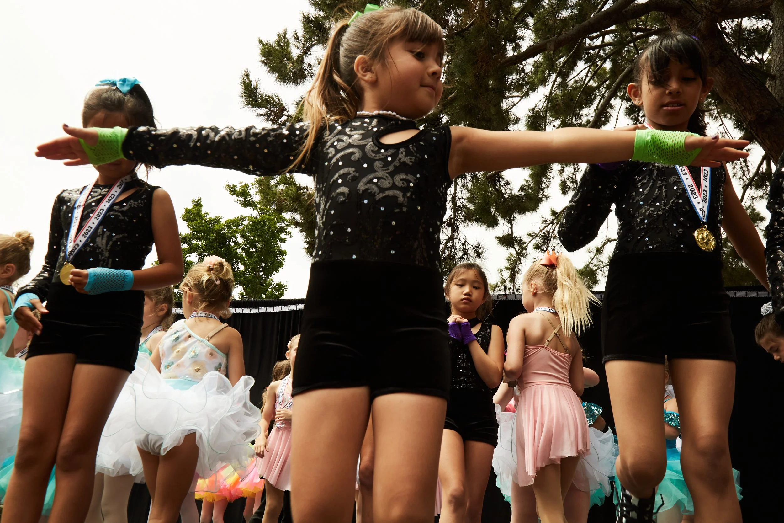 Young girls in dance costumes participating in a group performance outdoors.