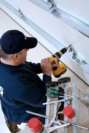 using a cordless drill on metal brackets mounted to a wall, with tools and a tool bag nearby.