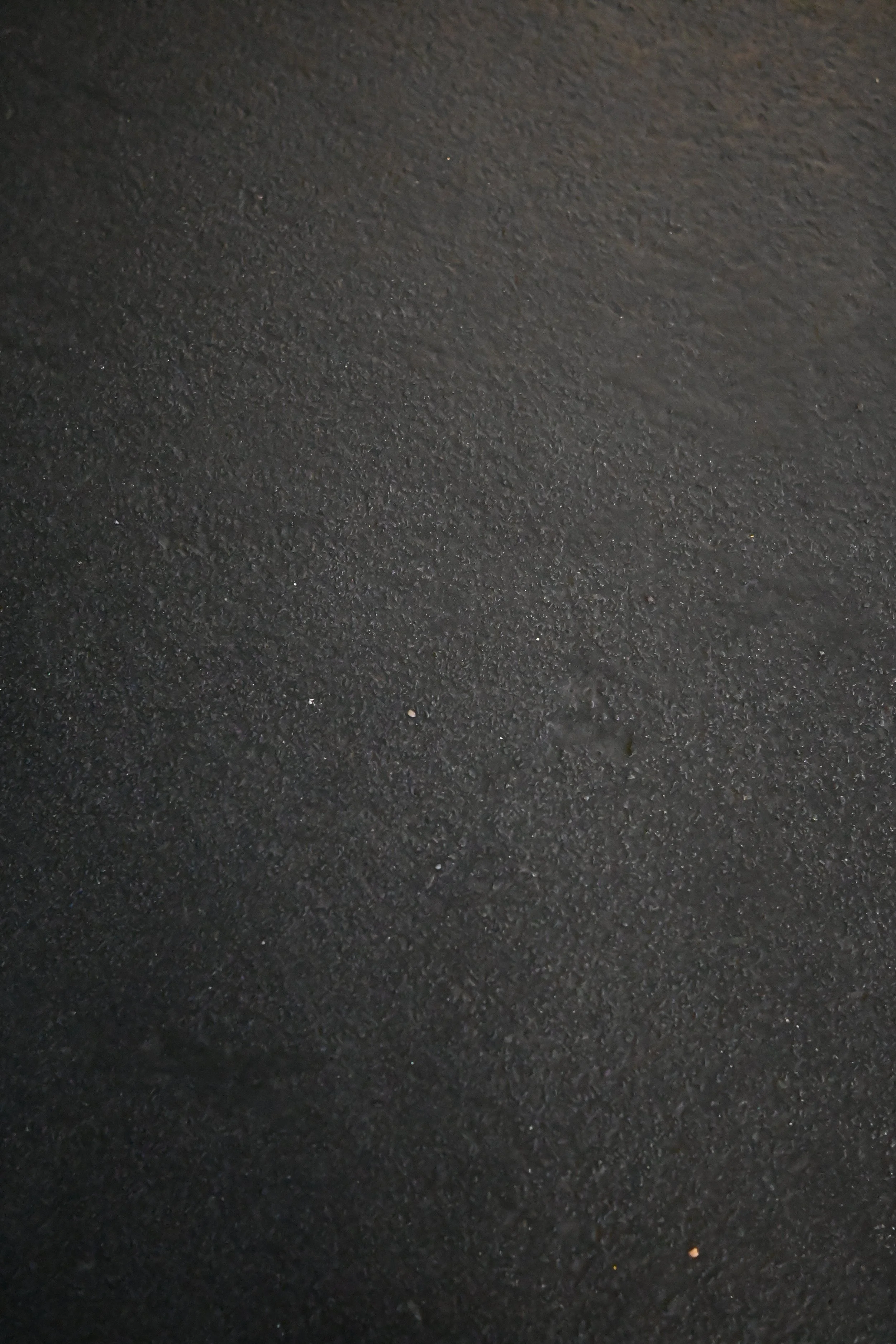 Close-up of a textured black asphalt surface with small scattered pebbles.