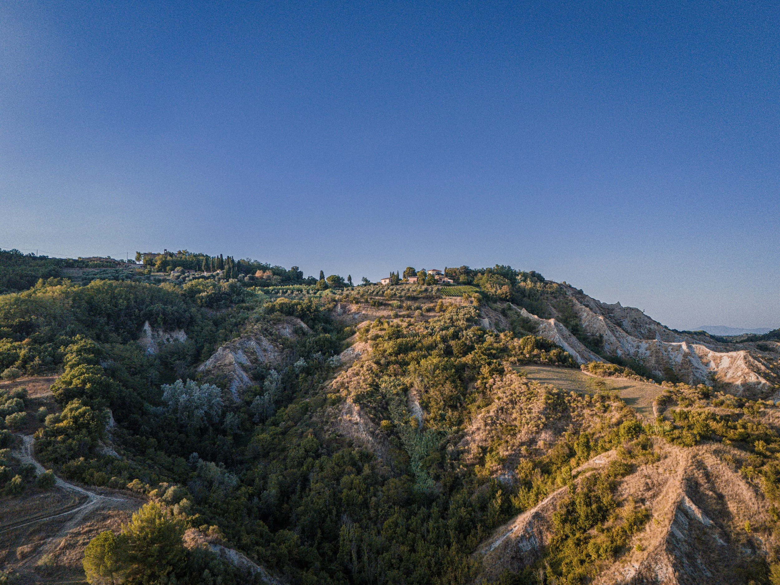 Paysage de collines avec végétation dense et terrasses agricoles sous un ciel clair.