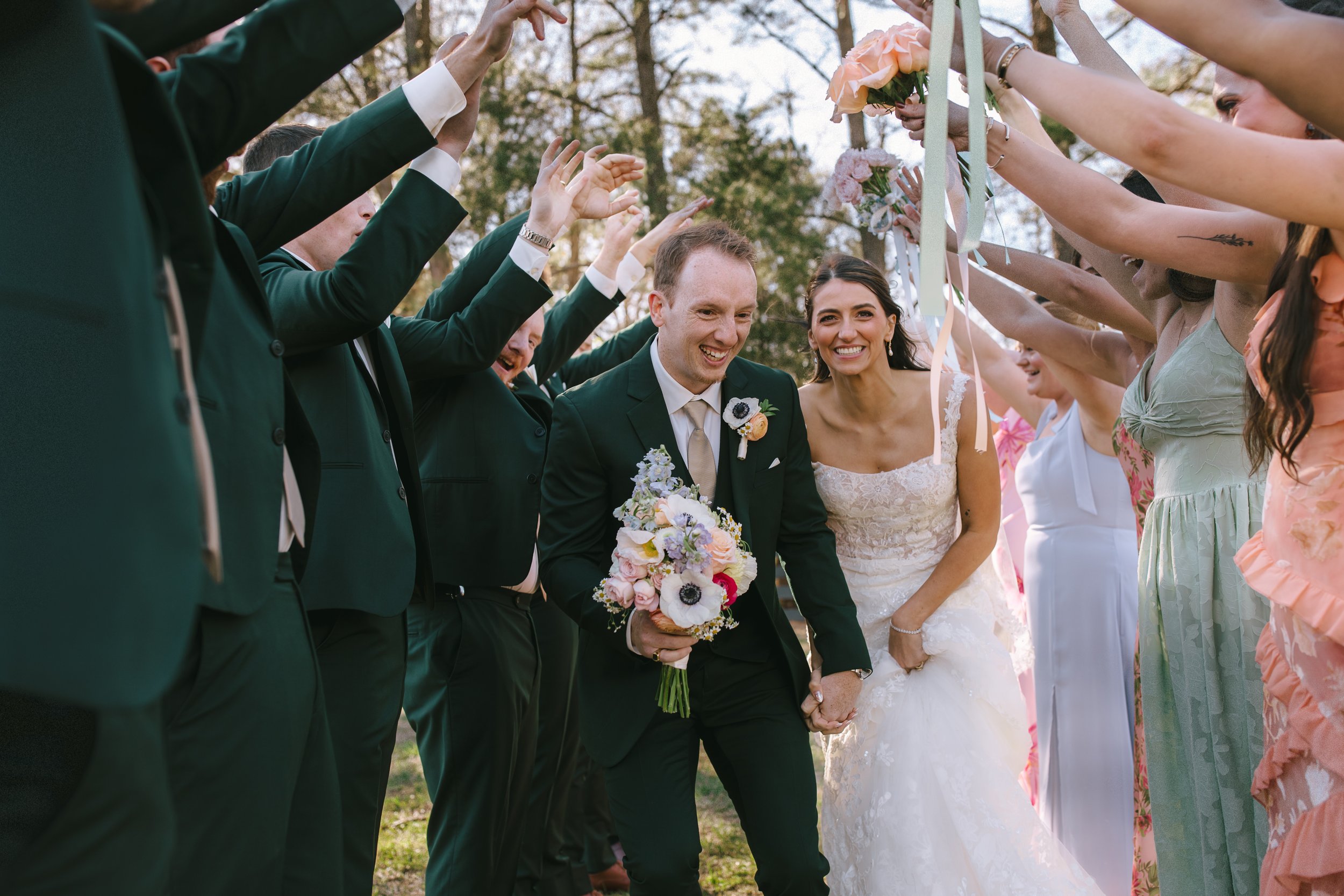 Close-up of a bride and groom holding the bouquet at their wedding ceremony, with the bride dressed in white and the groom in a dark suit.