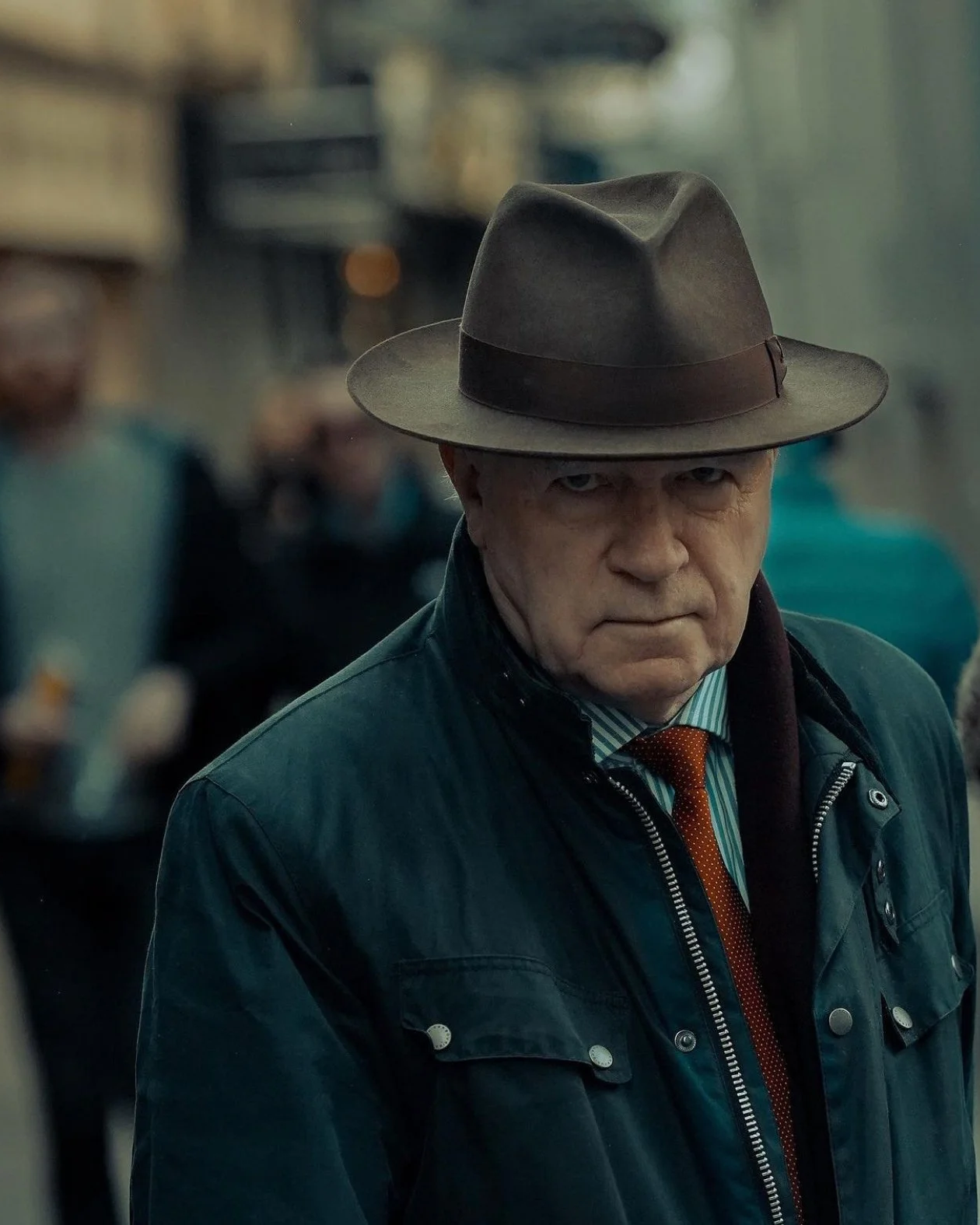 Street portrait of an older man in a brown hat and coat on a busy Dublin street - photo by Daniya.