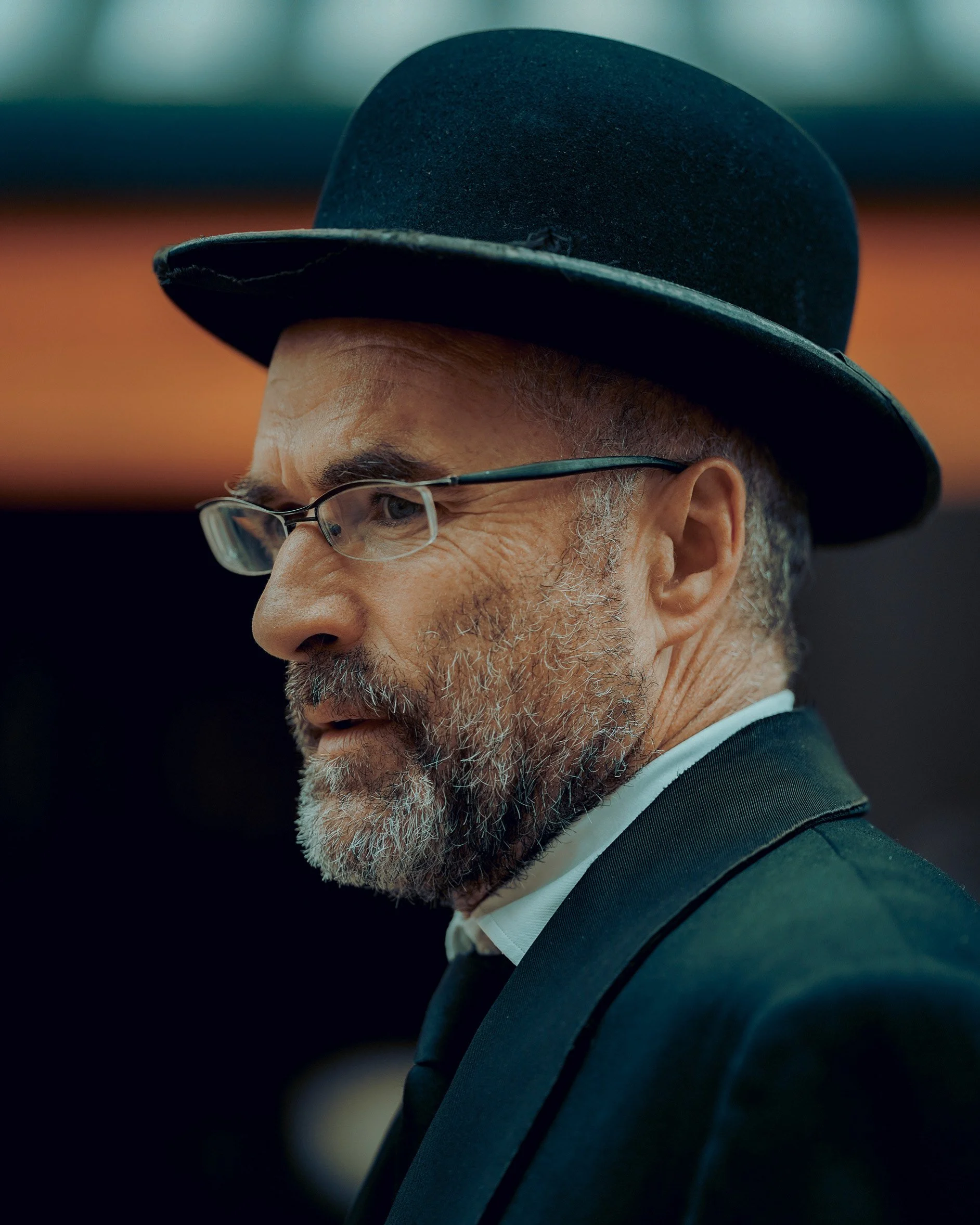 Close-up candid Dublin street portrait of an older man in a hat and glasses, intense expression - Photo by Daniya 