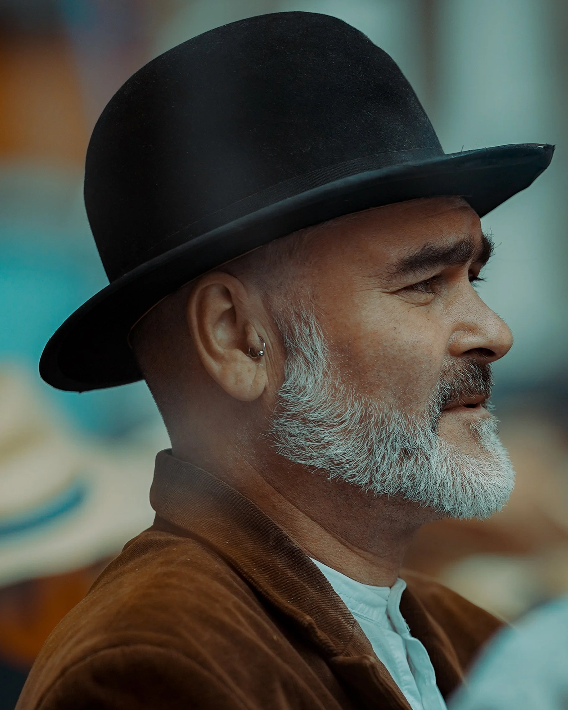 Close-up candid Dublin street portrait of a young man in a brown coat and dark hat, moody tones, cinematic style 