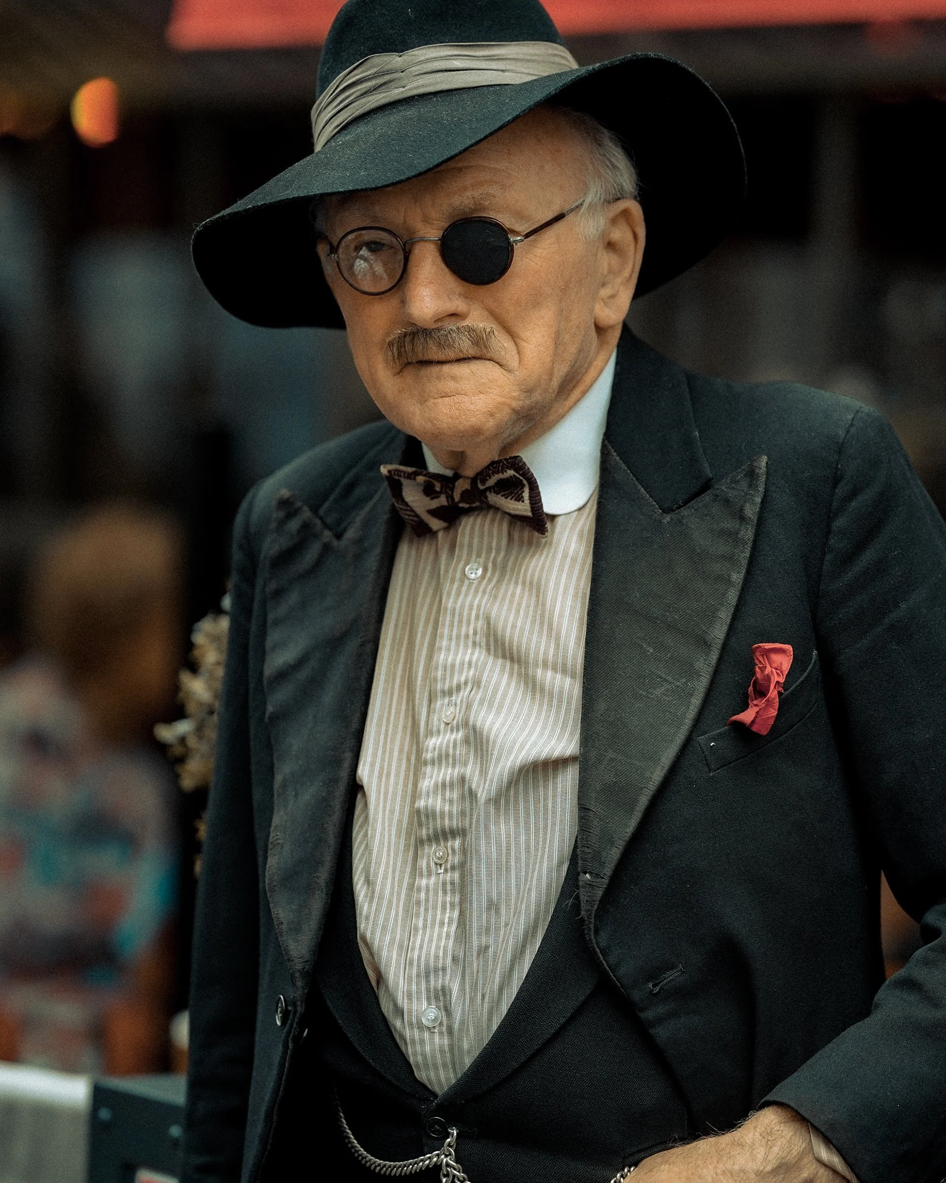 Vintage Dublin street portrait of an older man in a black suit, round glasses, and wide-brimmed hat – Photo by Daniya, street photography.