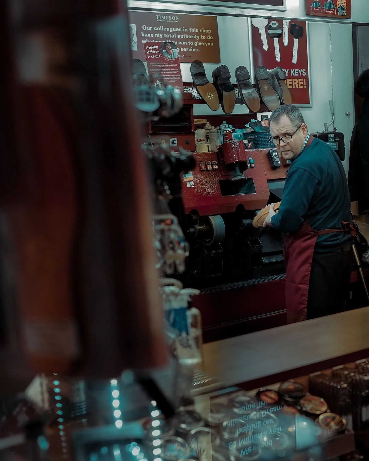 Candid Dublin street portrait of a shoemaker repairing shoes in his workshop, captured in a natural moment — Photo by Daniya, street photography.