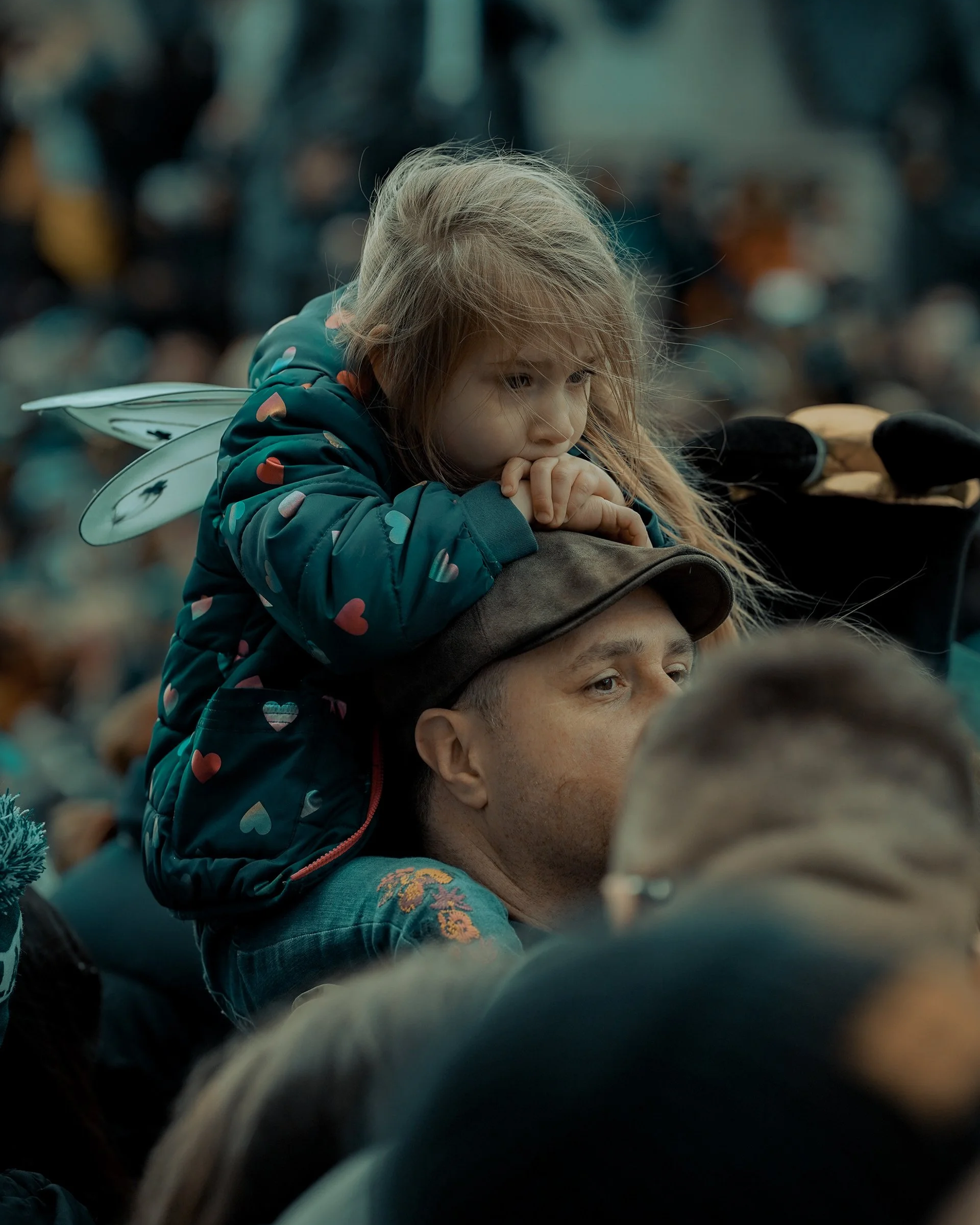 Candid moment of a little girl with fairy wings sitting on her father’s shoulders in a crowd — Dublin street photography, Photo by Daniya.