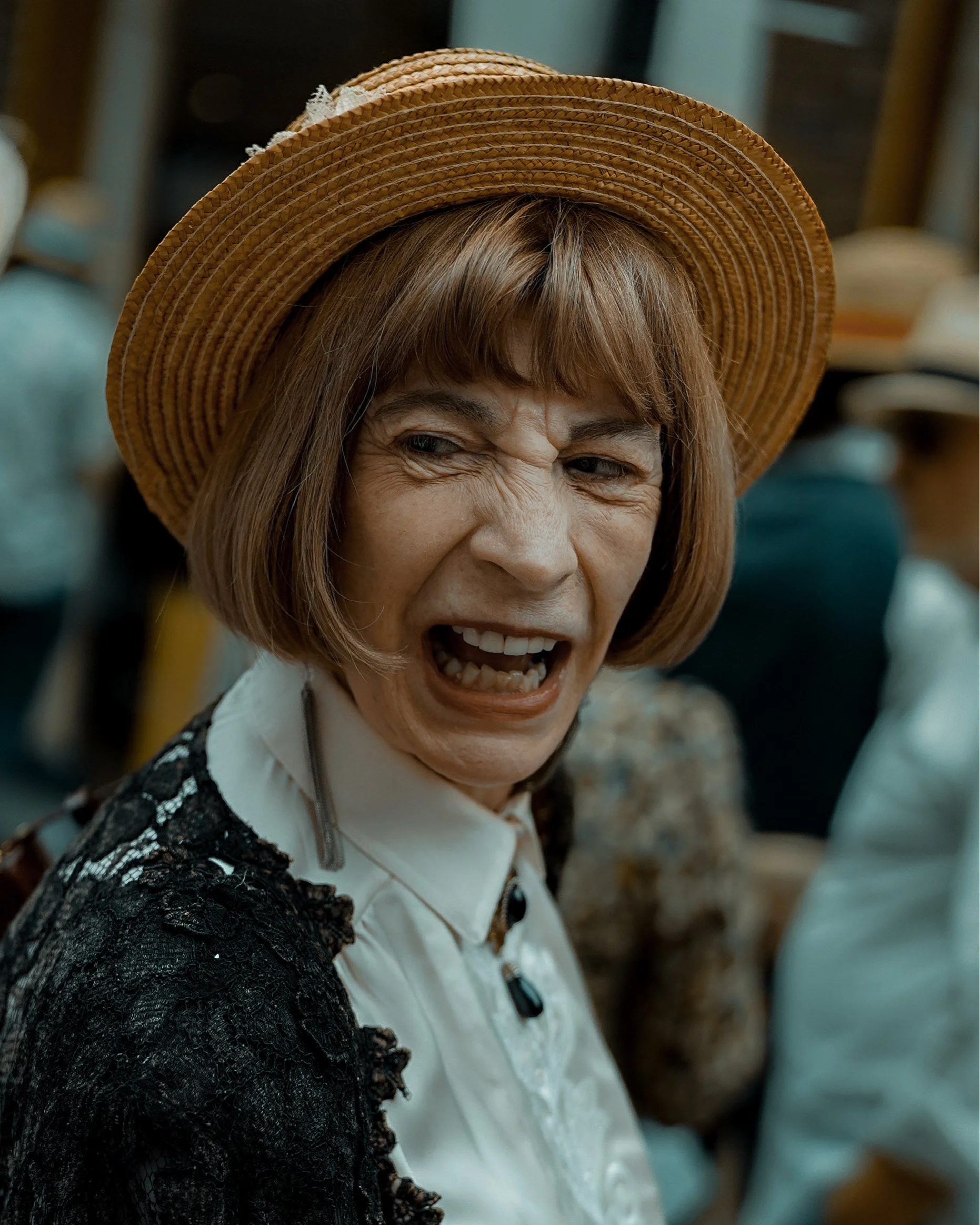 Expressive candid portrait of a woman in a vintage straw hat, laughing in the crowd — Dublin street photography, Photo by Daniya.