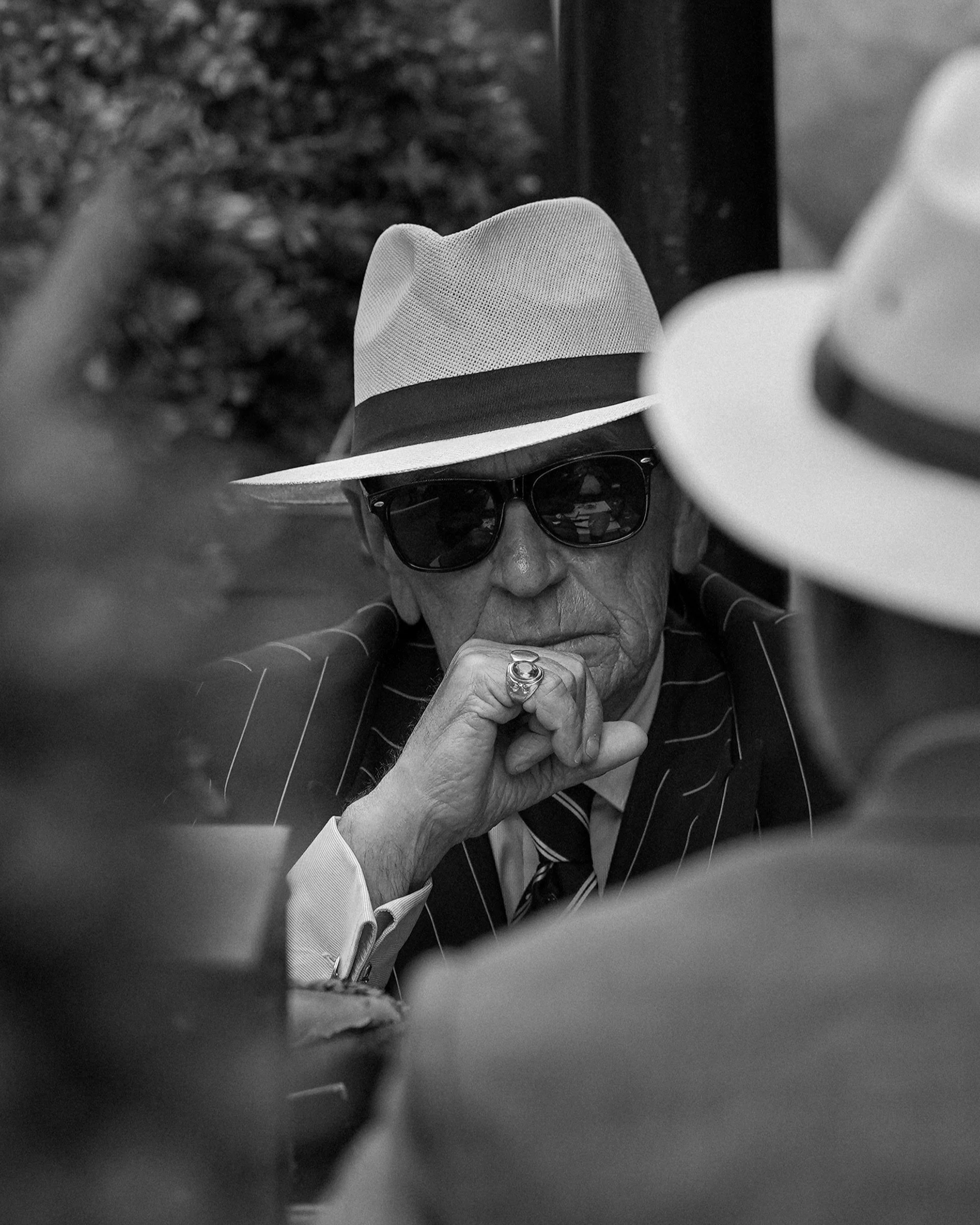 Black and white candid of a stylish man in a fedora and sunglasses, cinematic street portrait — Dublin street photography, Photo by Daniya.
