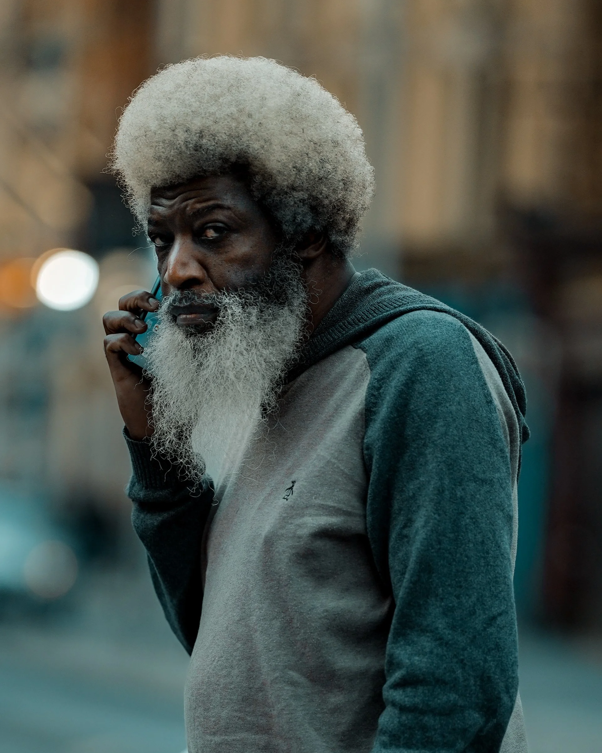 Street portrait of a man with a grey afro hairstyle and long beard, wearing a hoodie, candid Dublin street photography.