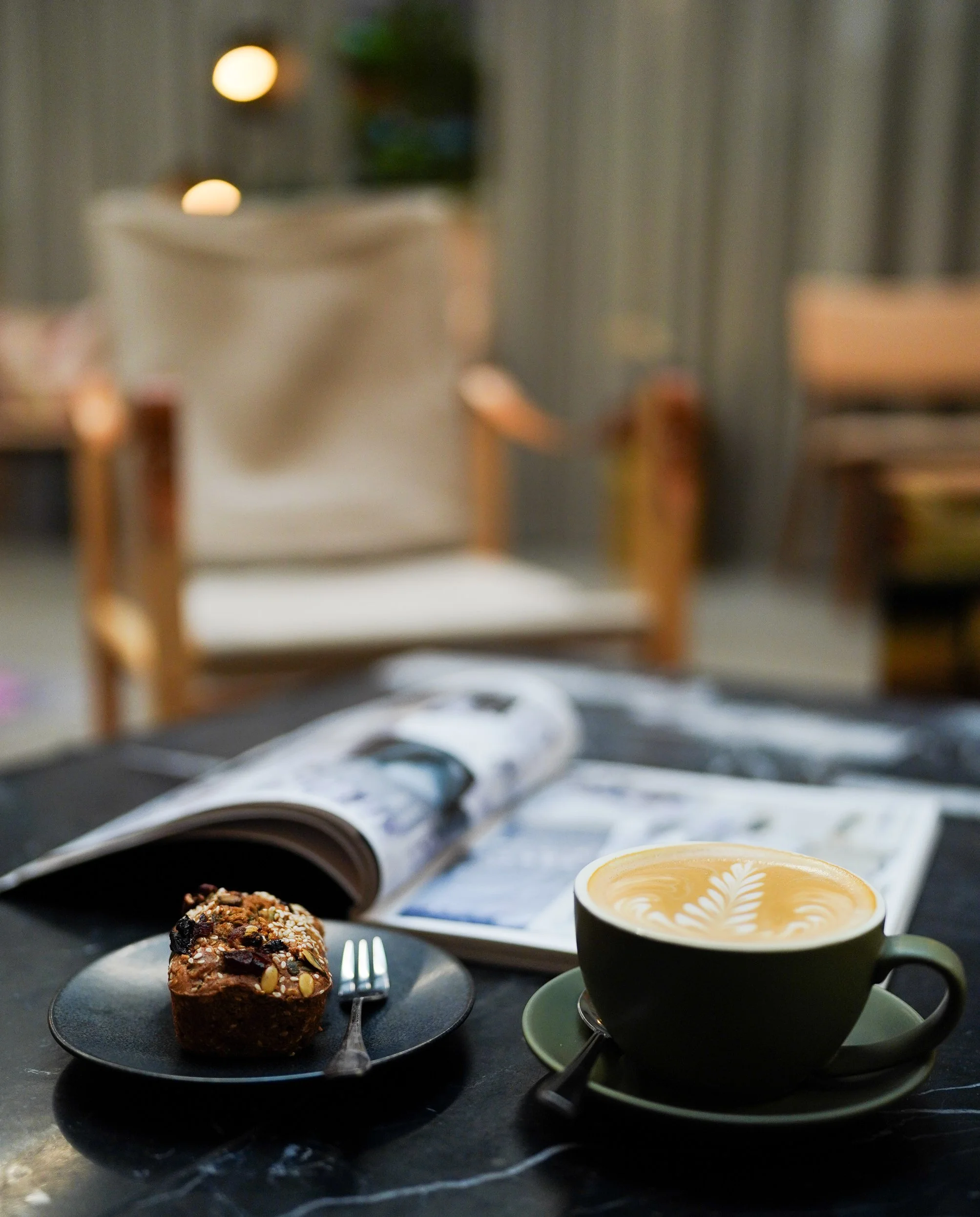 Latte with magazine and dessert on café table, Dublin coffee shop.