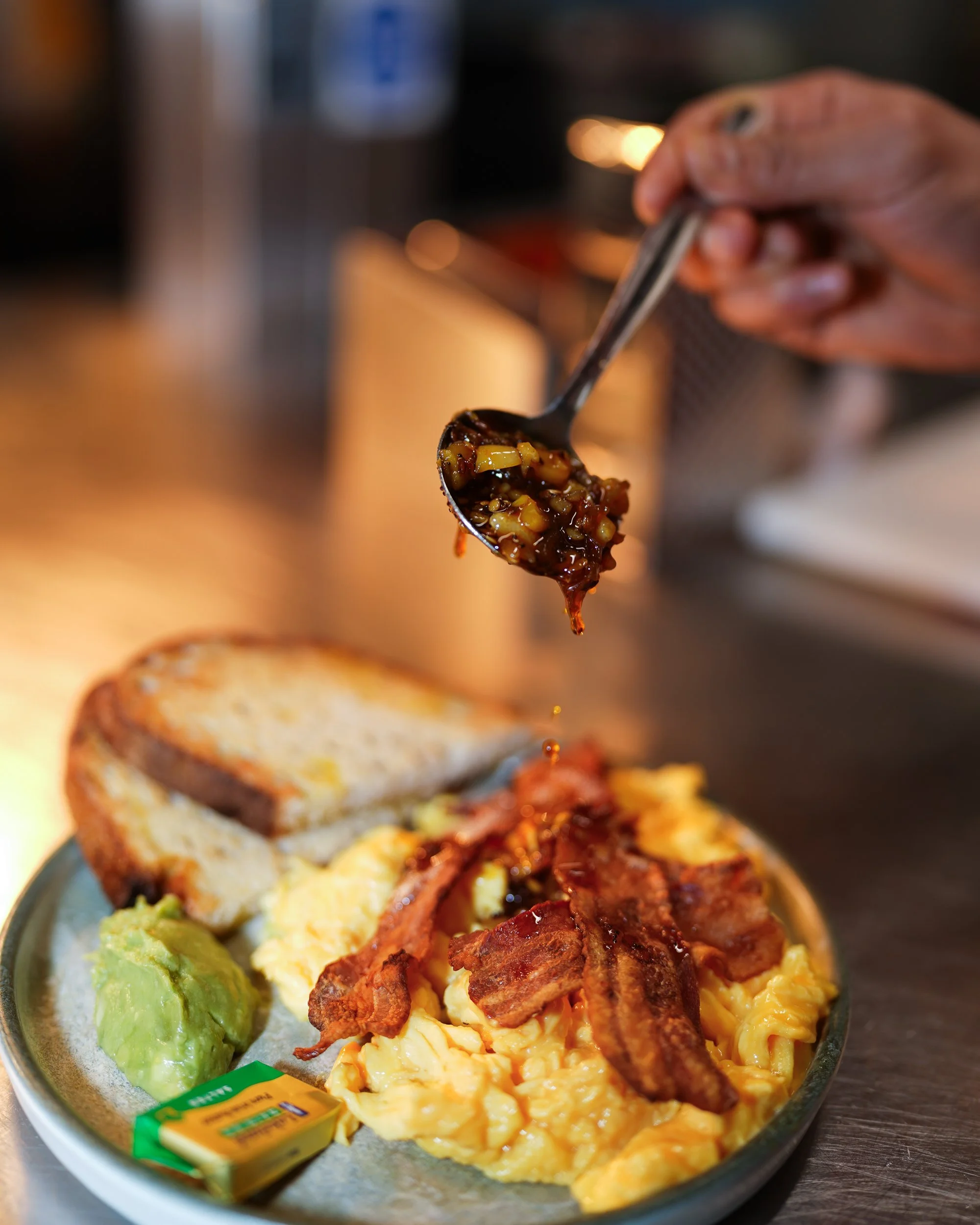 Scrambled eggs with bacon and toast on a restaurant plate.