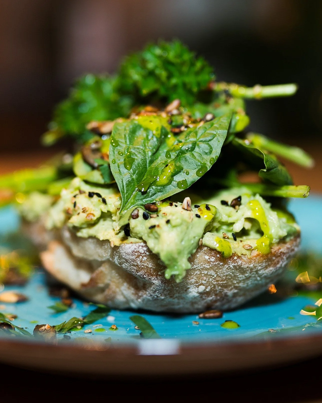 Avocado toast with herbs and seeds on a blue plate.
