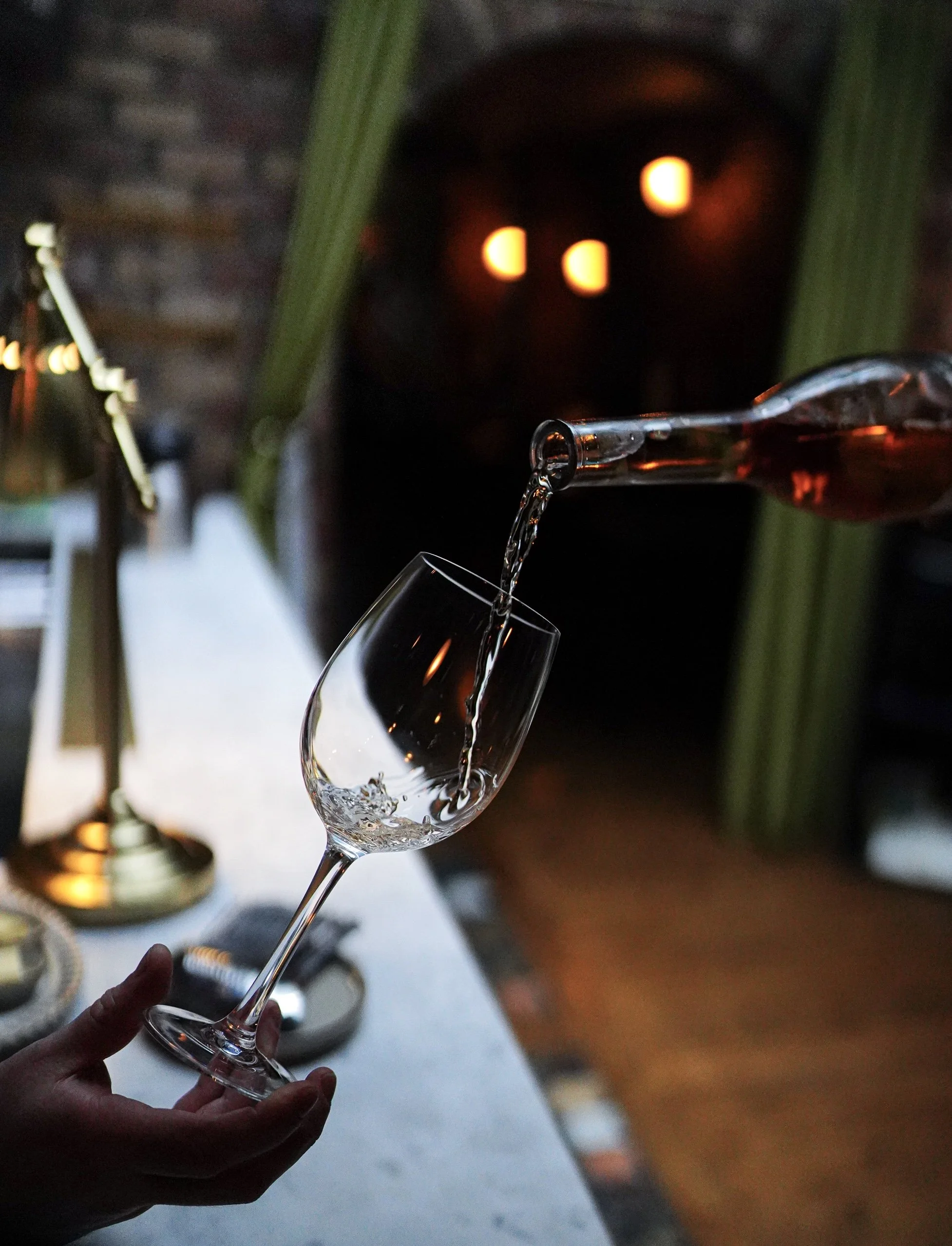 Waiter pouring rose wine into glass in fine dining restaurant.