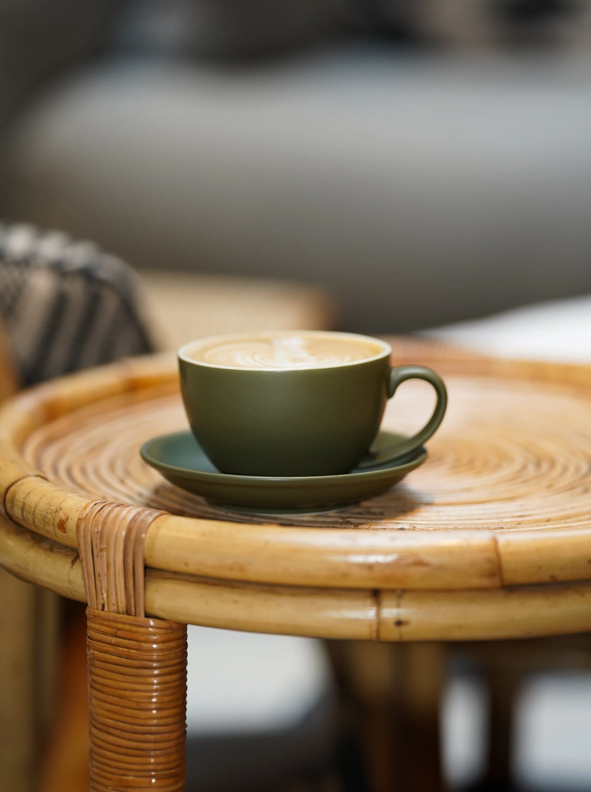 Green coffee cup with cappuccino on wooden café table.