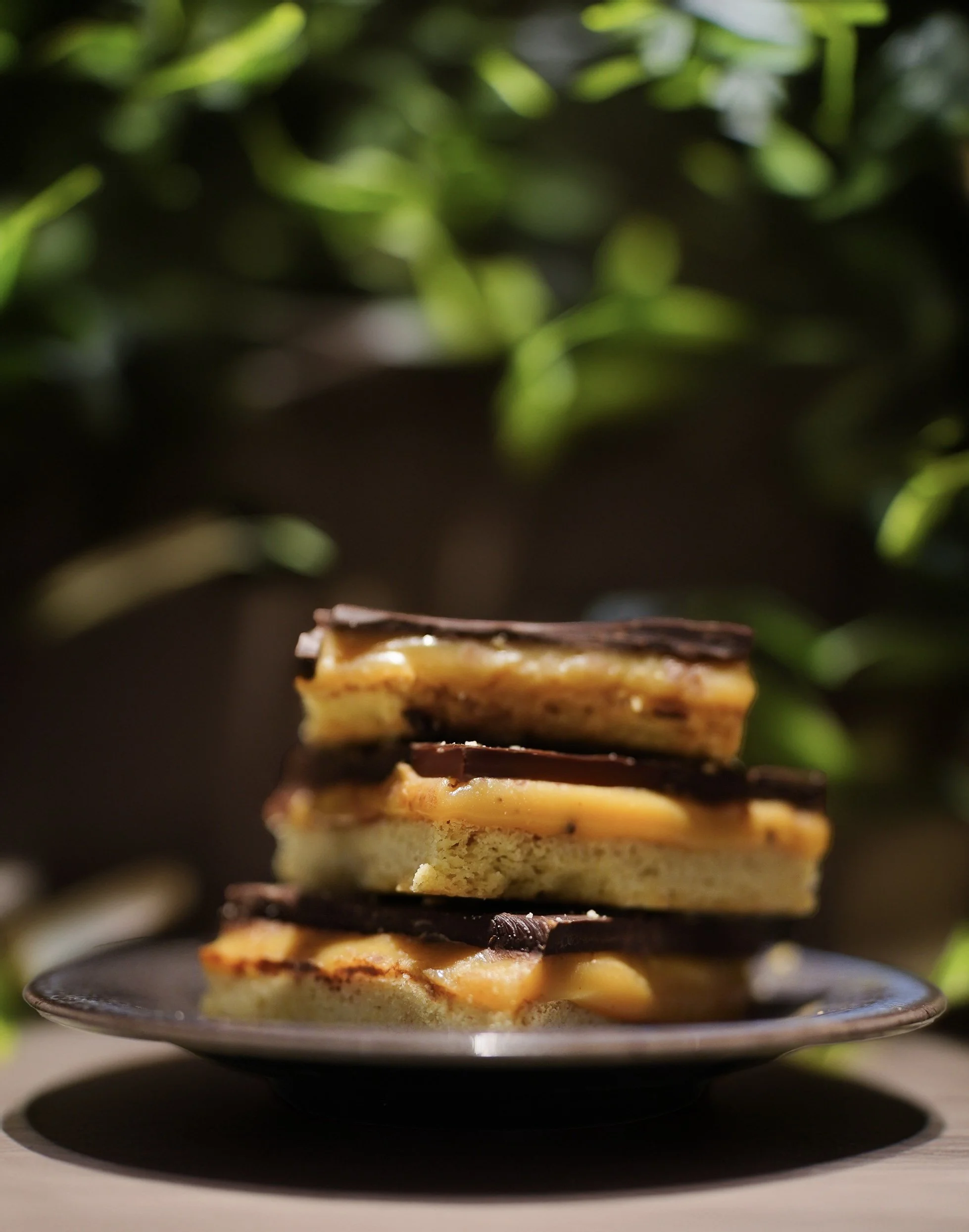 Stack of chocolate caramel dessert bars on a plate.