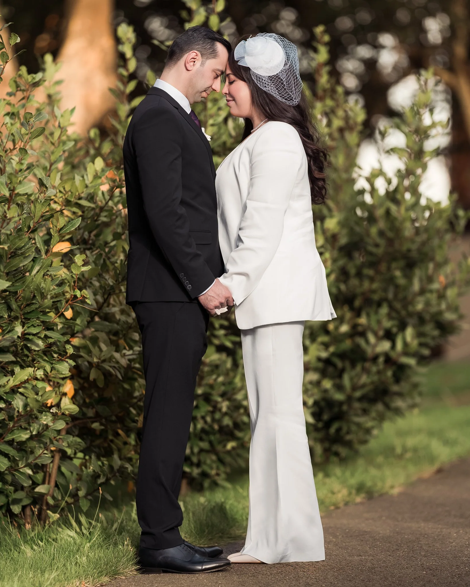 Groom gently holding his bride’s hand in a soft natural light, captured in Dublin gardens.