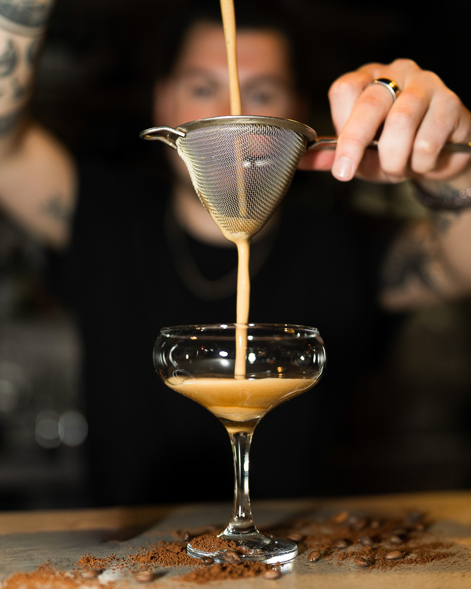 Bartender pouring Espresso Martini cocktail into elegant glass in restaurant.