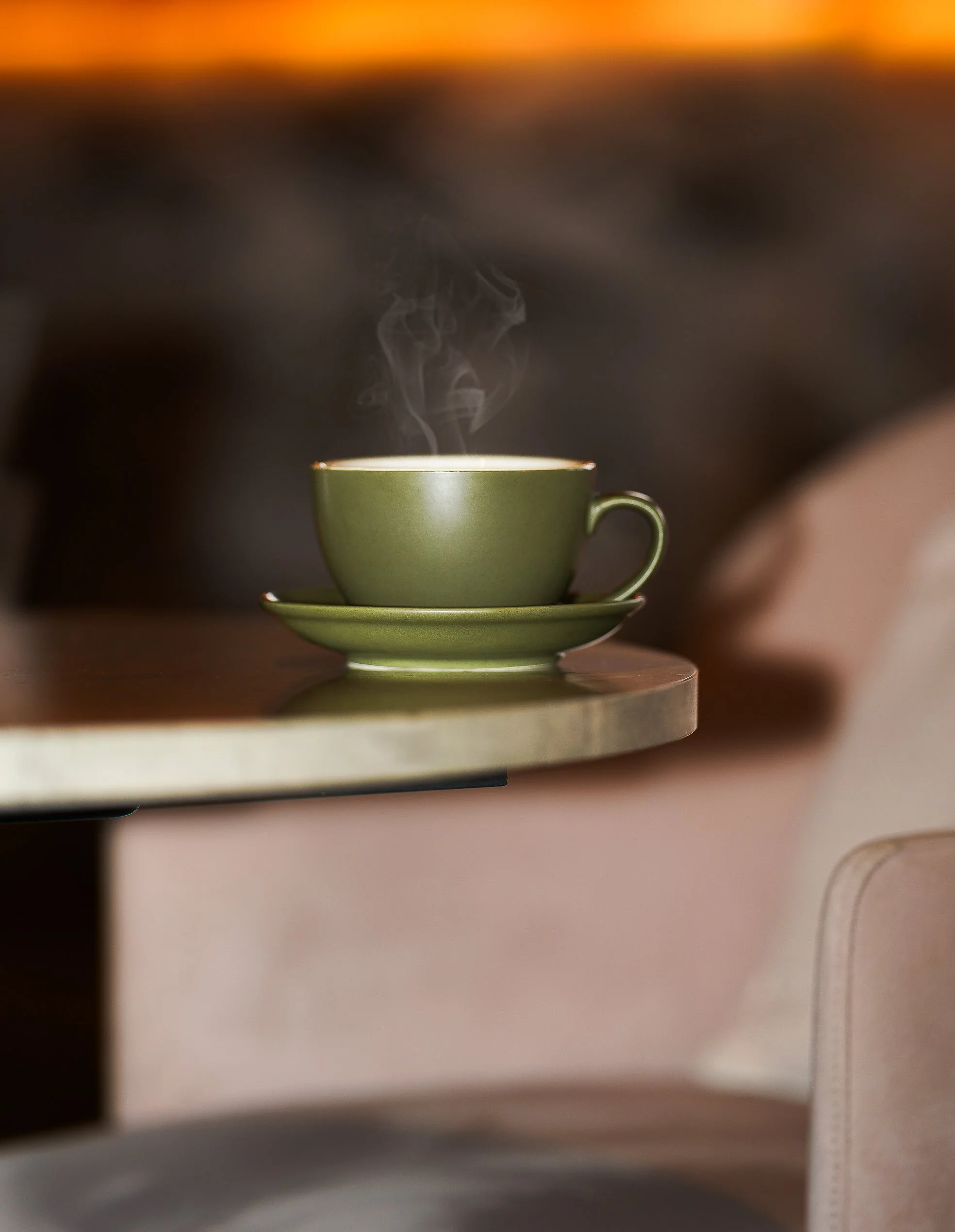 Green cup of steaming coffee on marble table in a cozy Dublin café.