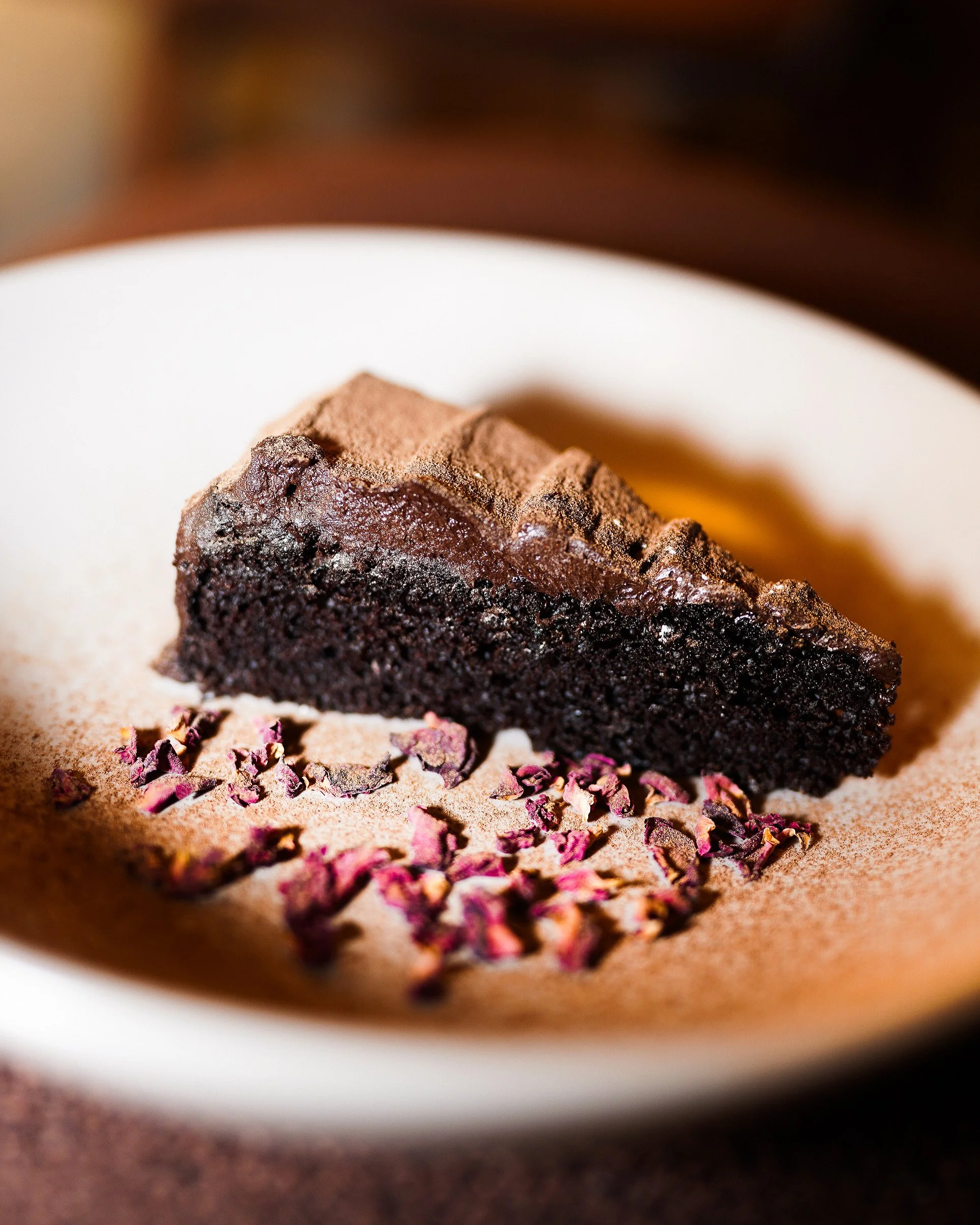 Rich chocolate cake with cream served on a white plate.