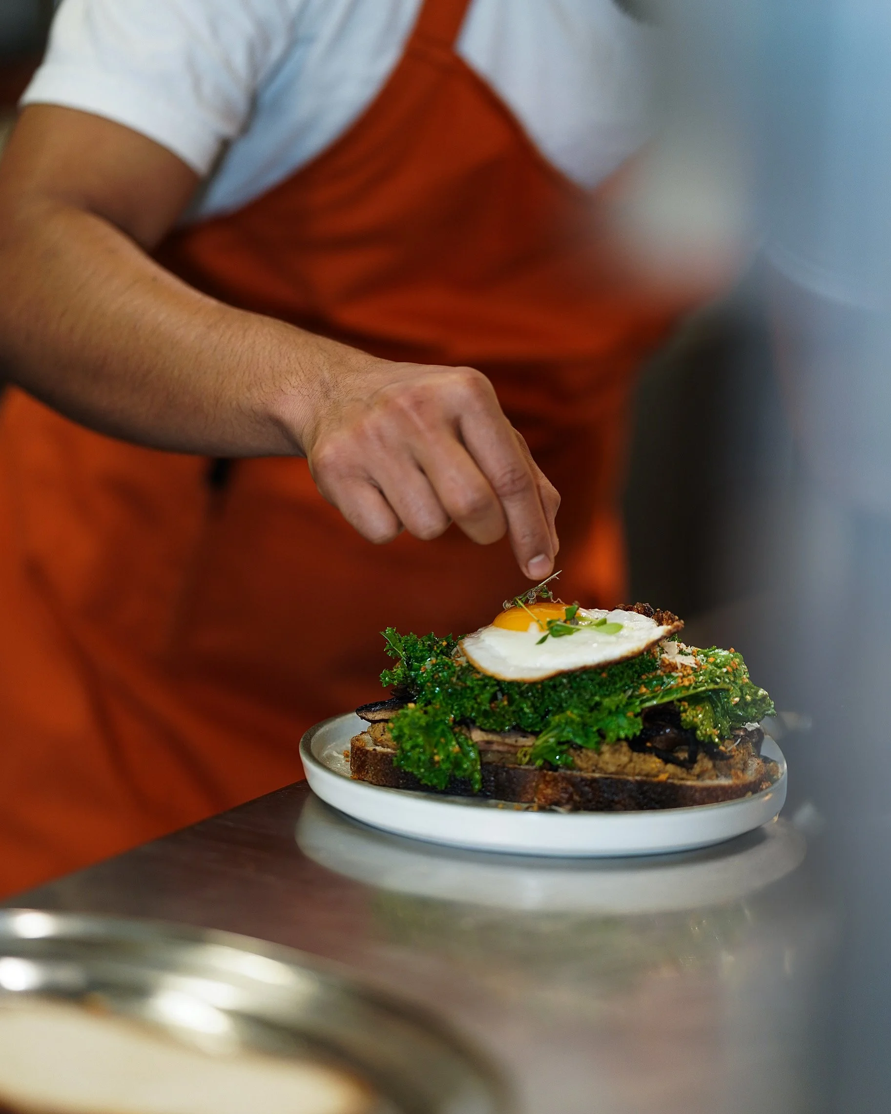 Chef preparing brunch plate with egg, avocado and fresh greens in Dublin café.