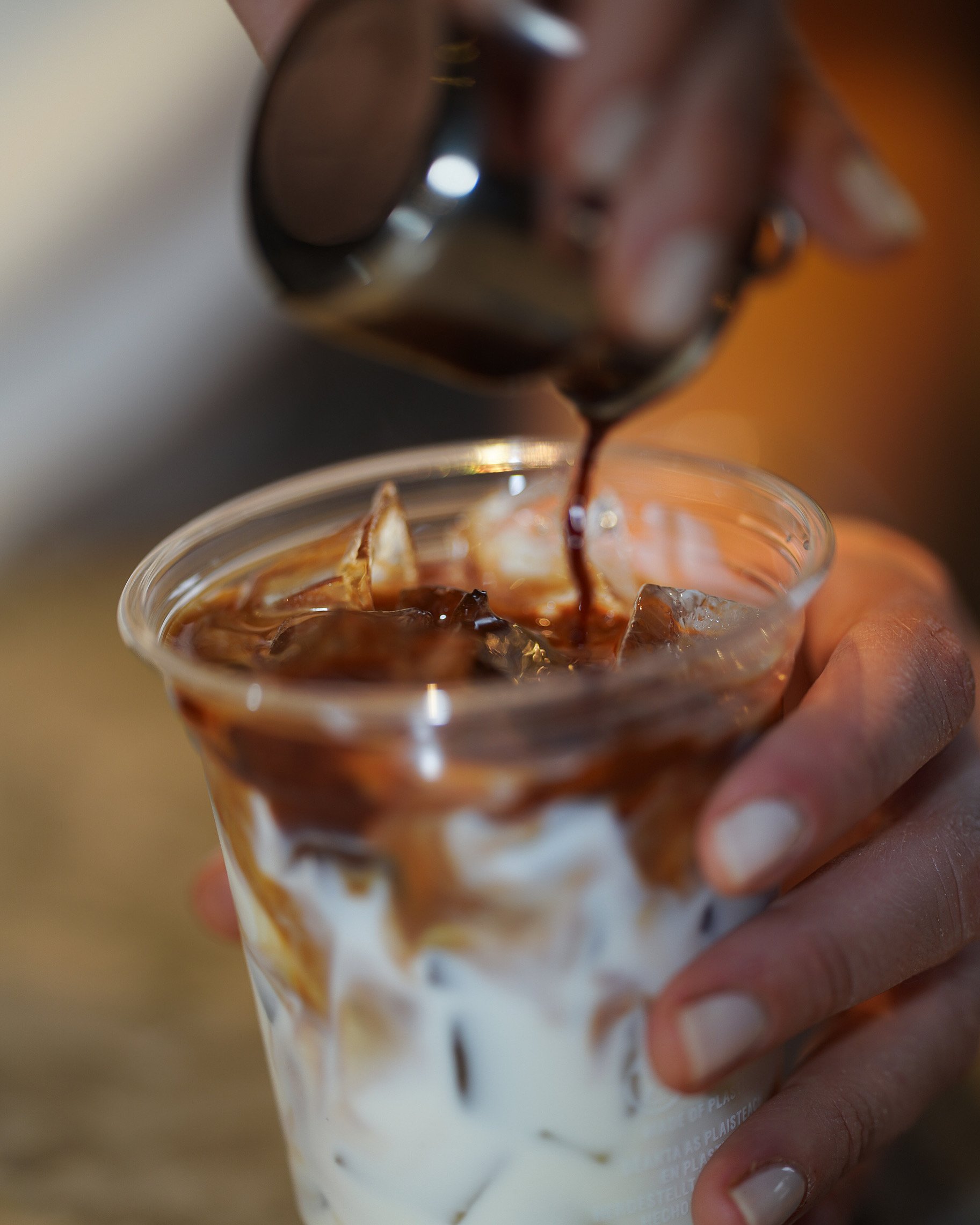 Iced latte in plastic cup with chocolate syrup drizzle.