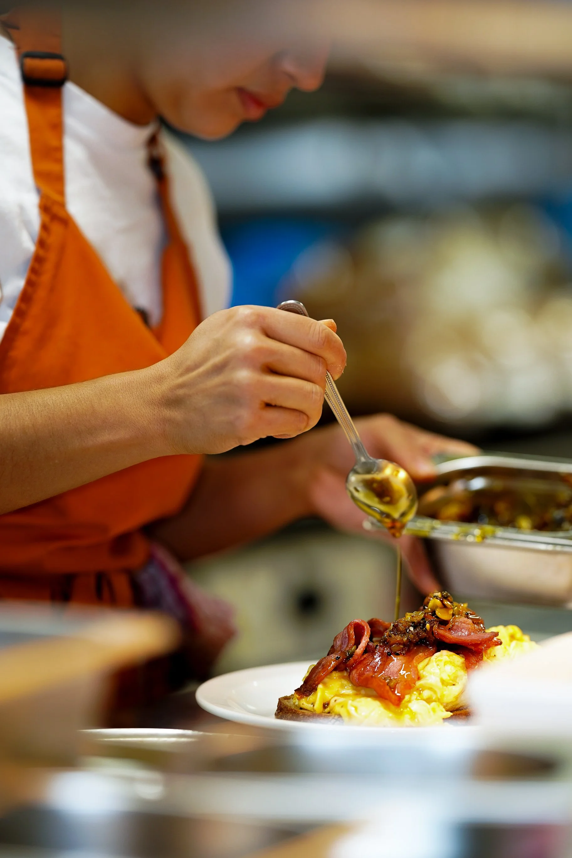 Chef in apron plating brunch meal in café kitchen.
