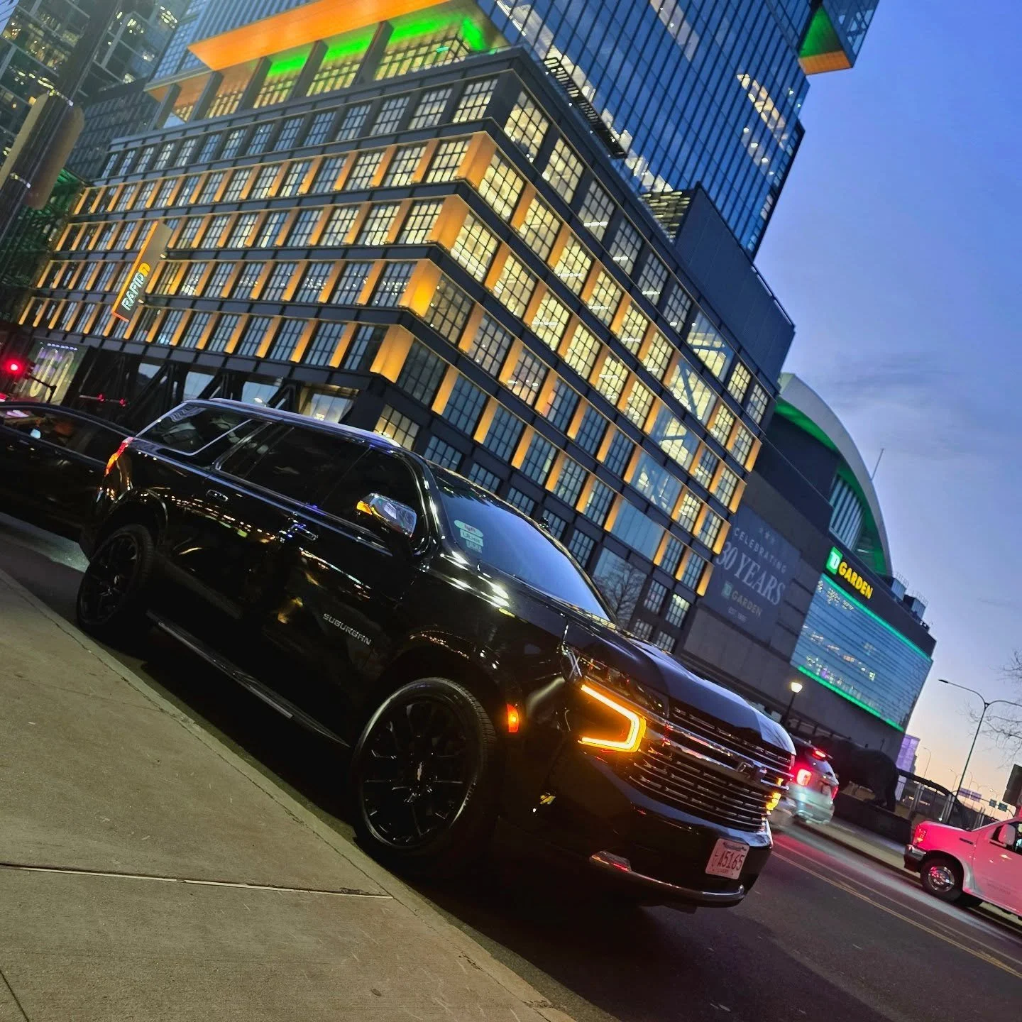A black Chevrolet Premier SUV parked near a stadium illuminated at night.