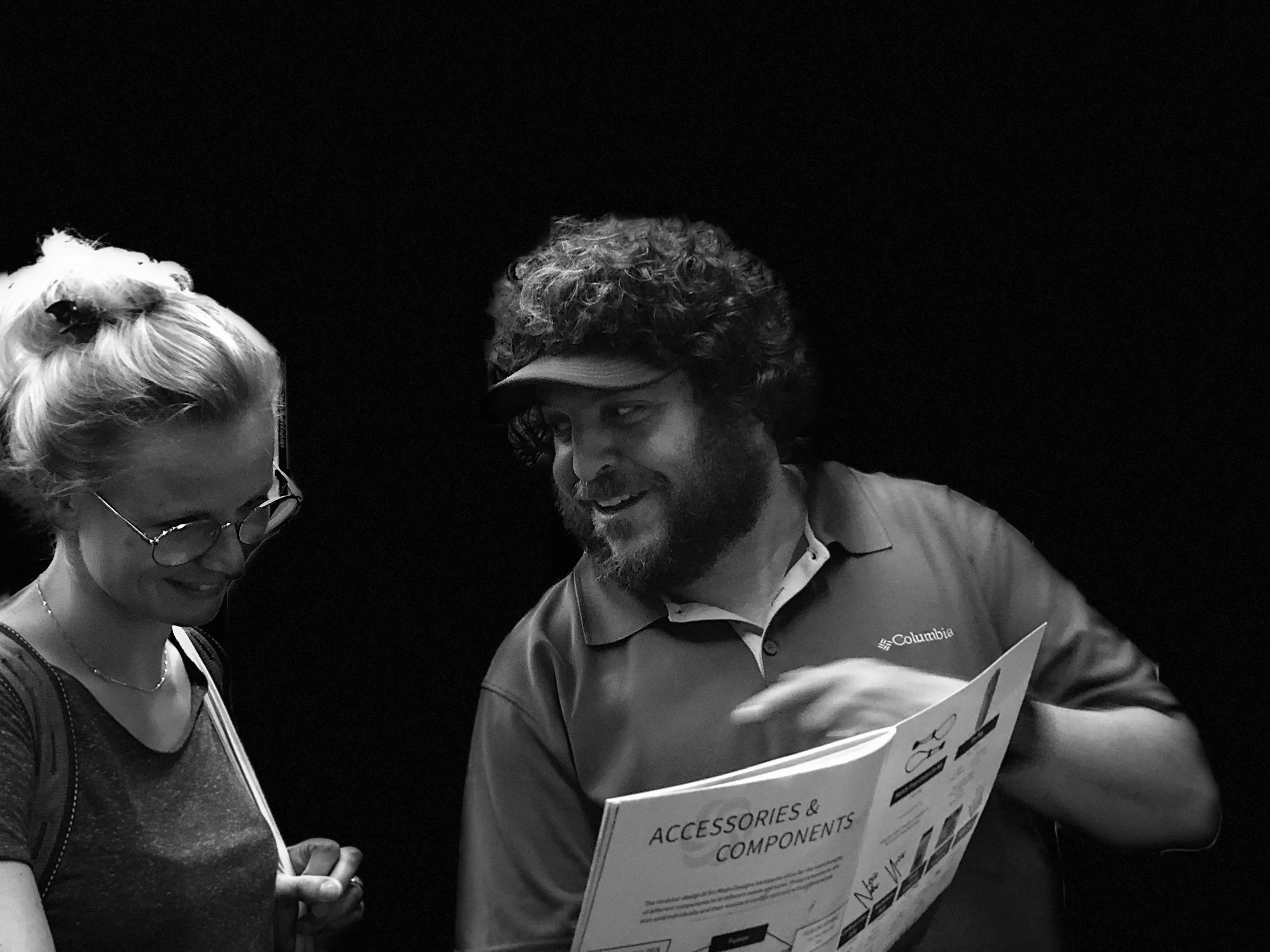 A slesperosn wearing a visor and holding catalog goes over the products offered with a potential customer