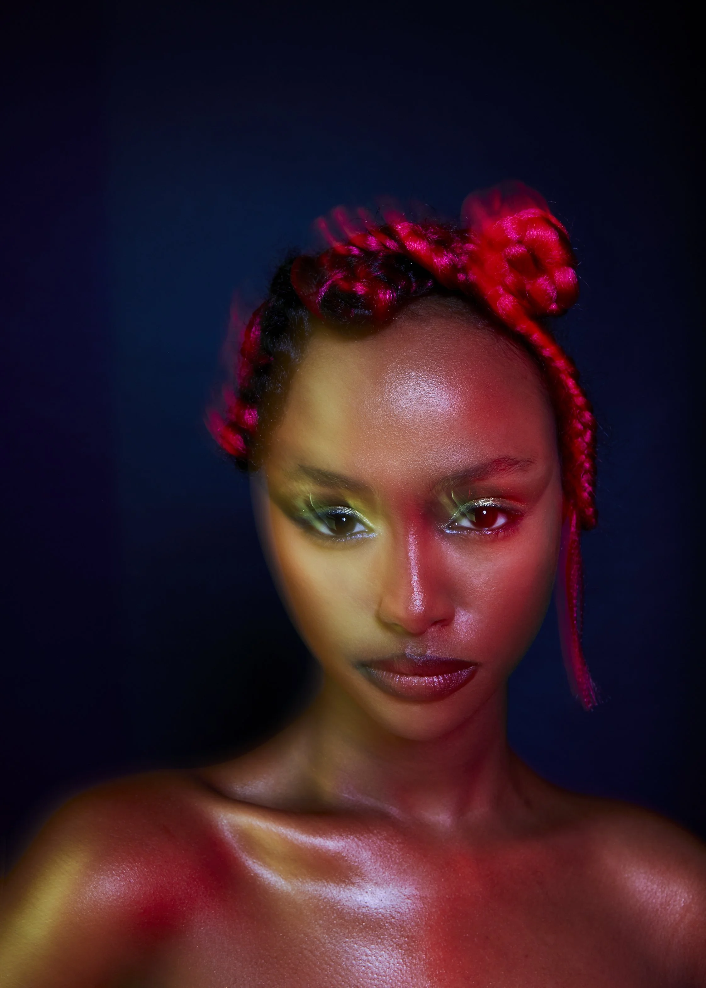 A cropped beauty image of a female model with green makeup and pink hair and blue background 