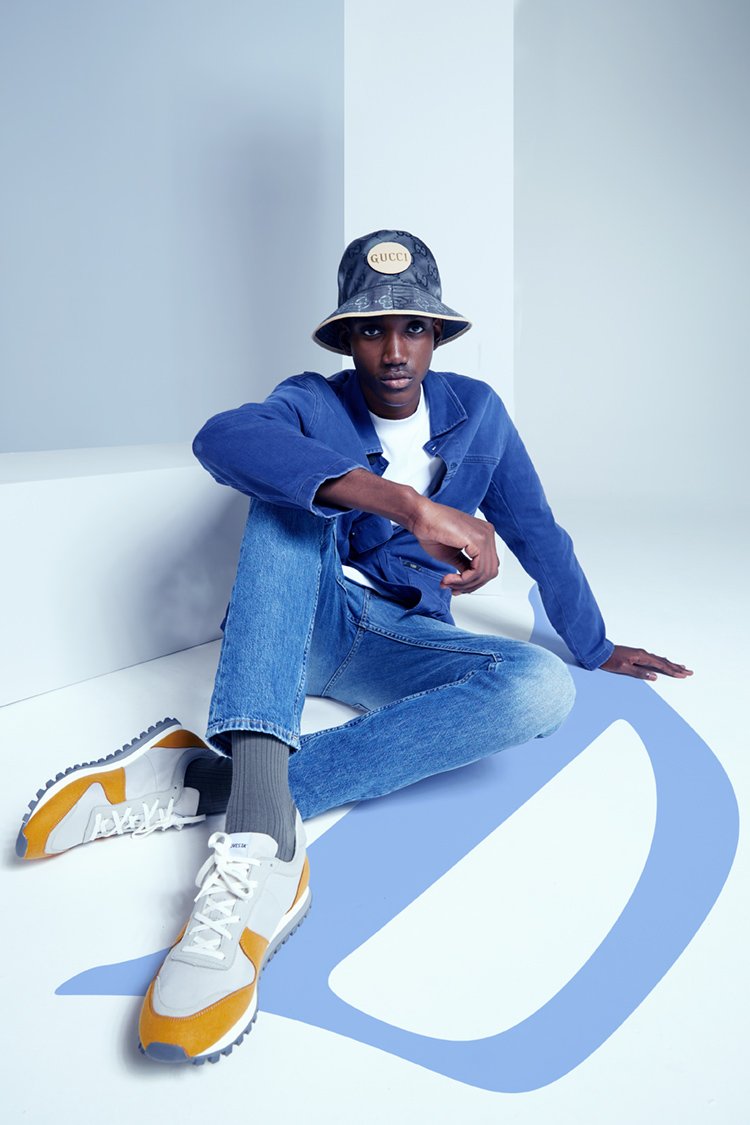 Fashion portrait of a man sitting crossed legged in denim clothing and hat