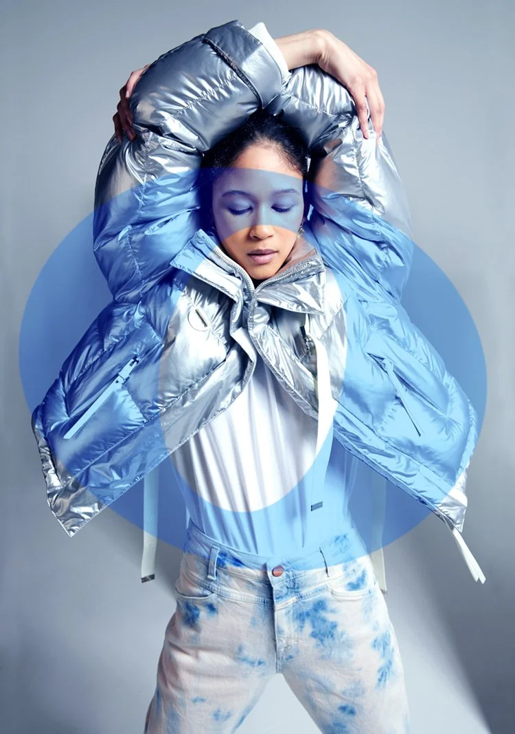 woman with arms stretched over her head in a silver jacket