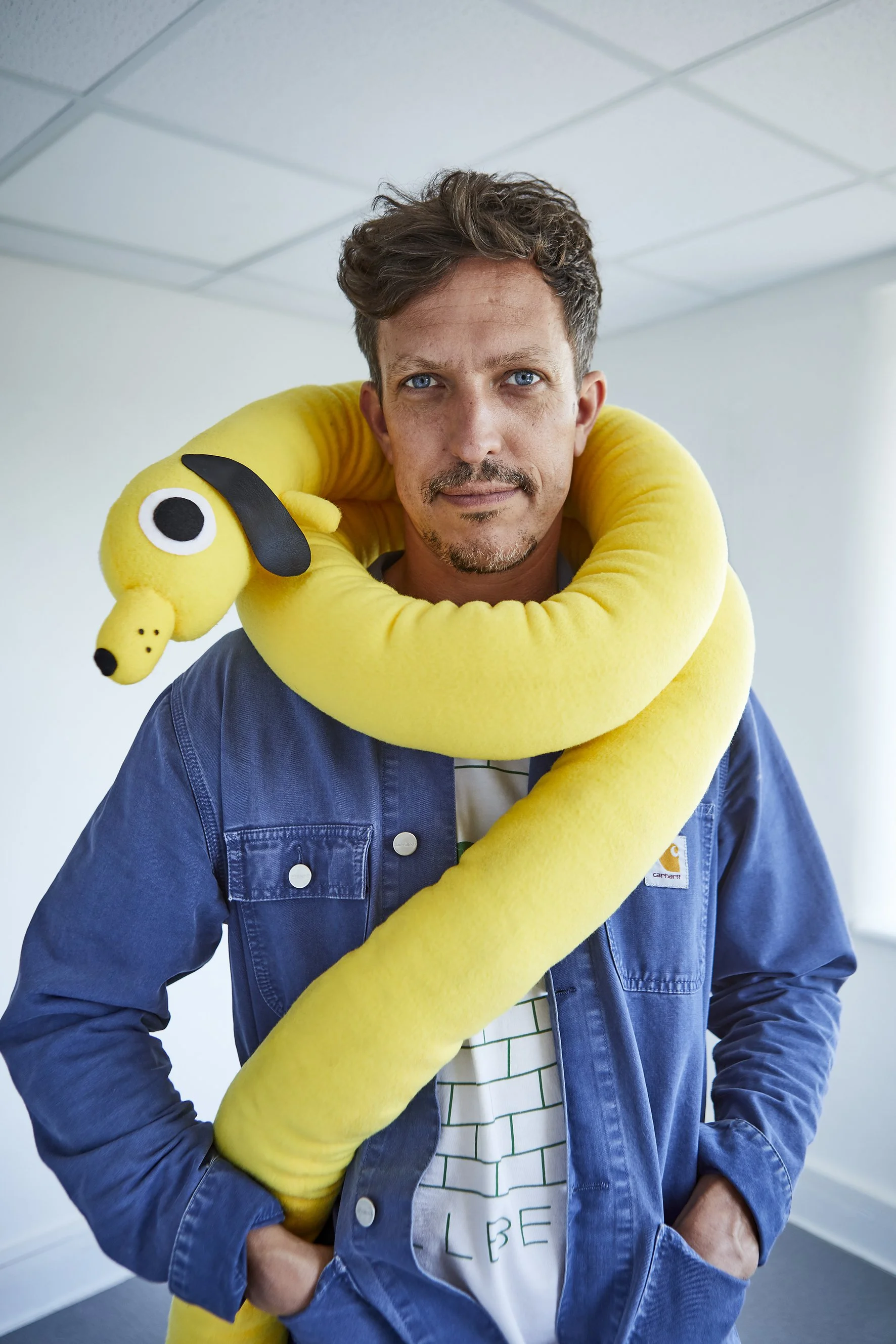 Portrait of white man with dark hair and toy dog wrapped around his neck