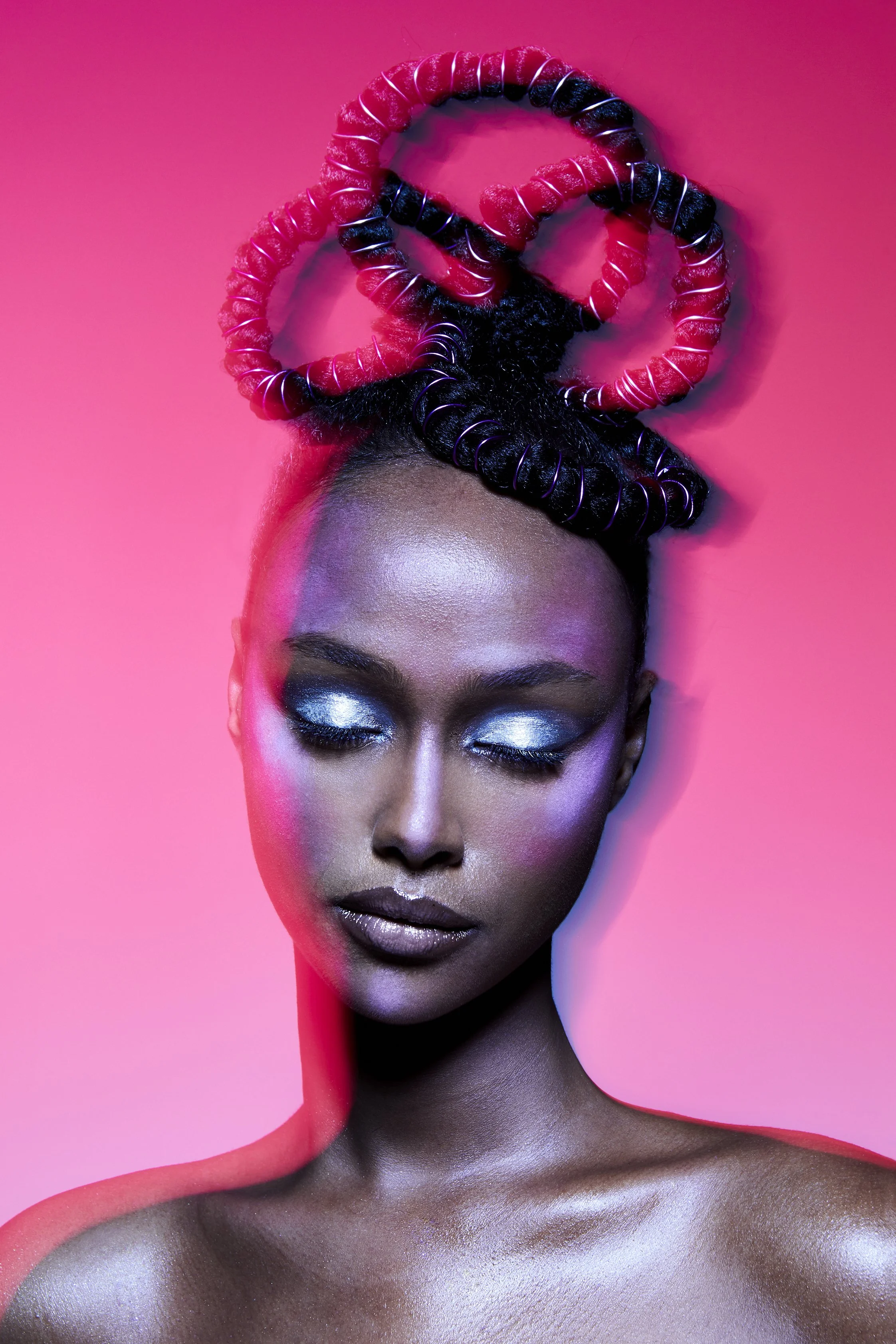 A cropped beauty image of a female model with silver makeup and pink background with eyes closed