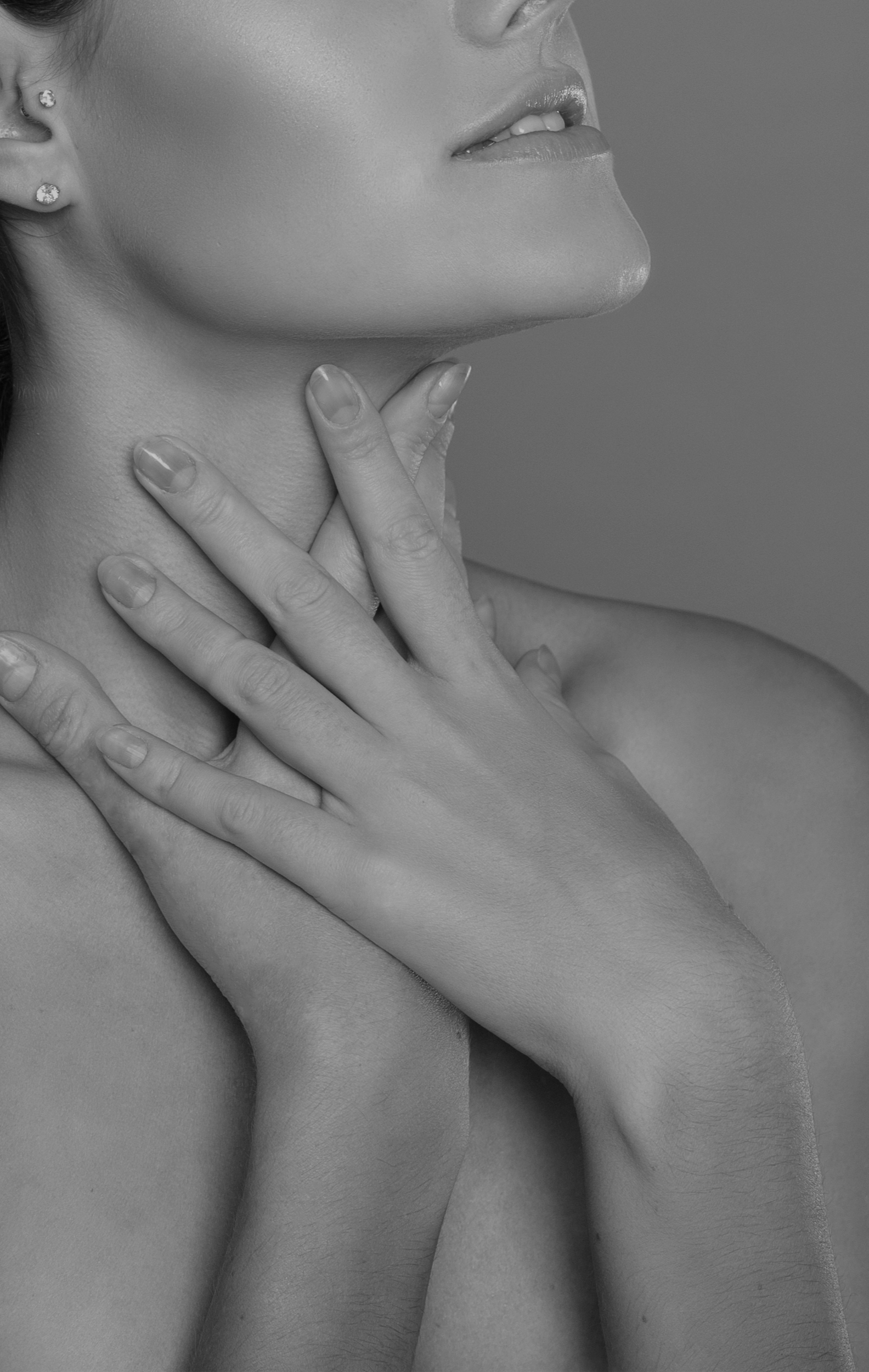 Nahaufnahme eines Frauenhalses und -gesichts, zeigt Hände, die den Hals berühren, in schwarz-weiß