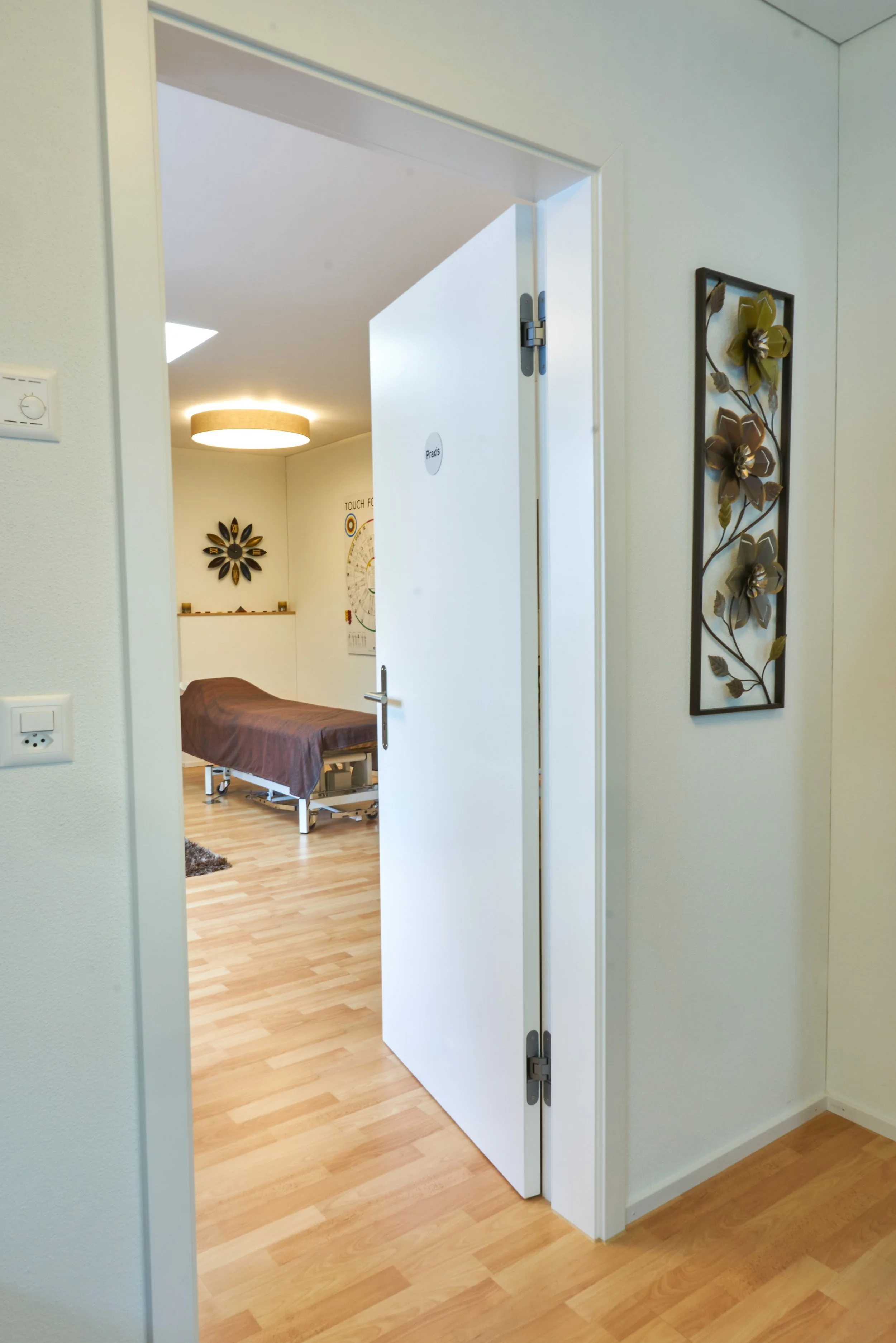 Hospitalzimmer mit einem halb offenen Tür, einem Krankenzimmer mit einem Bett, Lampen an der Decke, Wanddekoration und einer Skala auf der Wand.