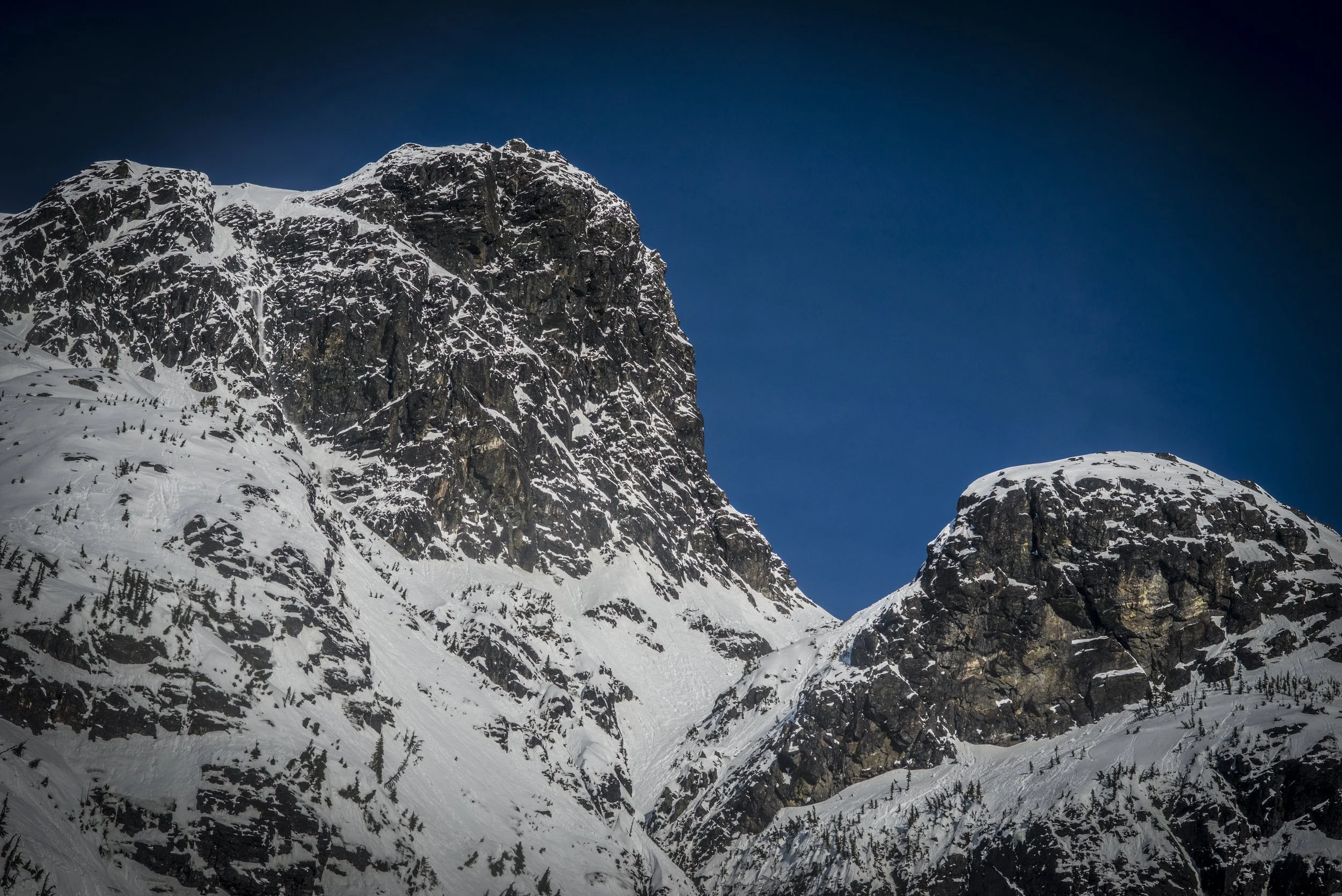 Snow-covered mountain peaks under a dark blue sky.