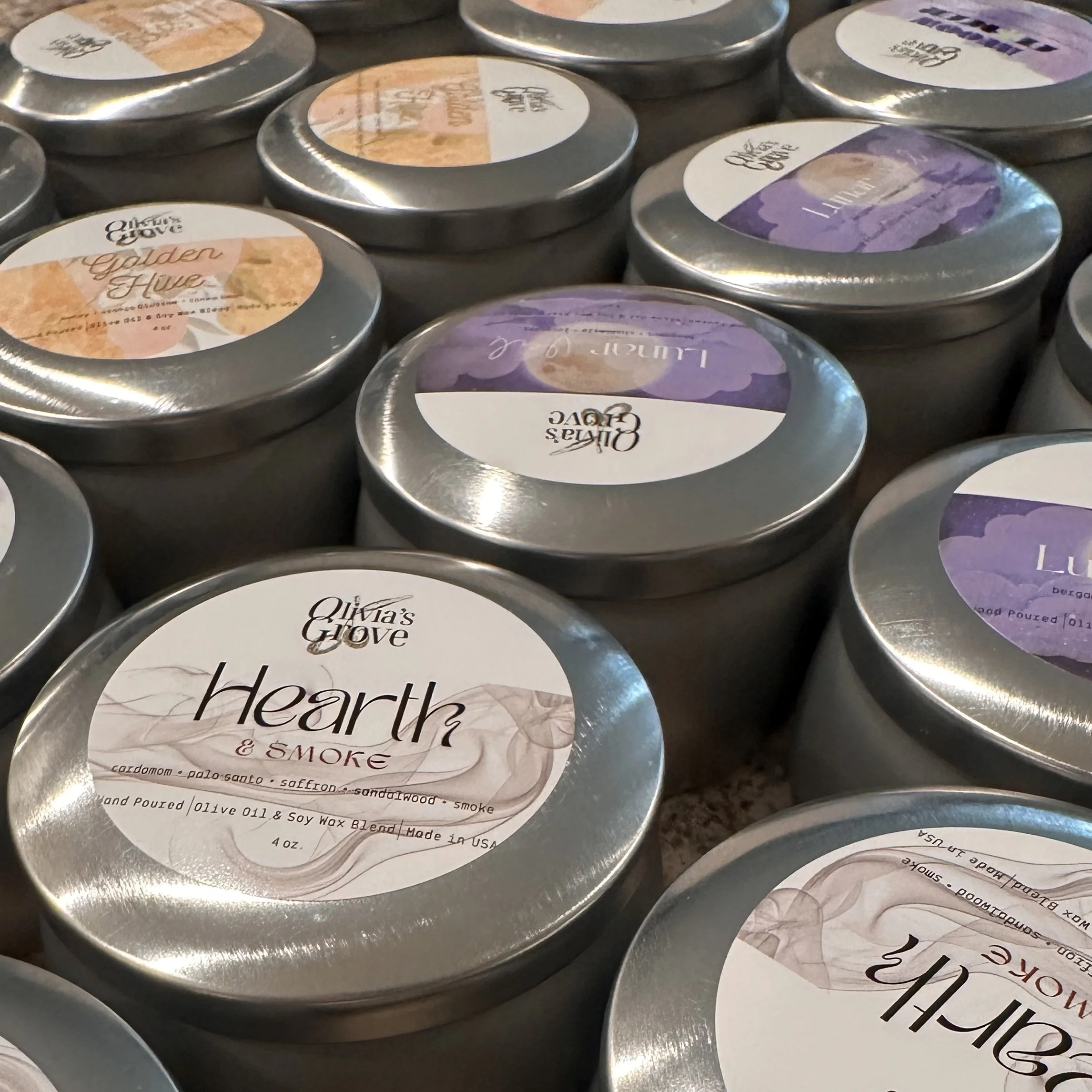 Multiple tins of scented wax melts from Olivia's GLOVE brand, with flavors 'Heart & Smoke' and 'Lavender' visible on some labels.