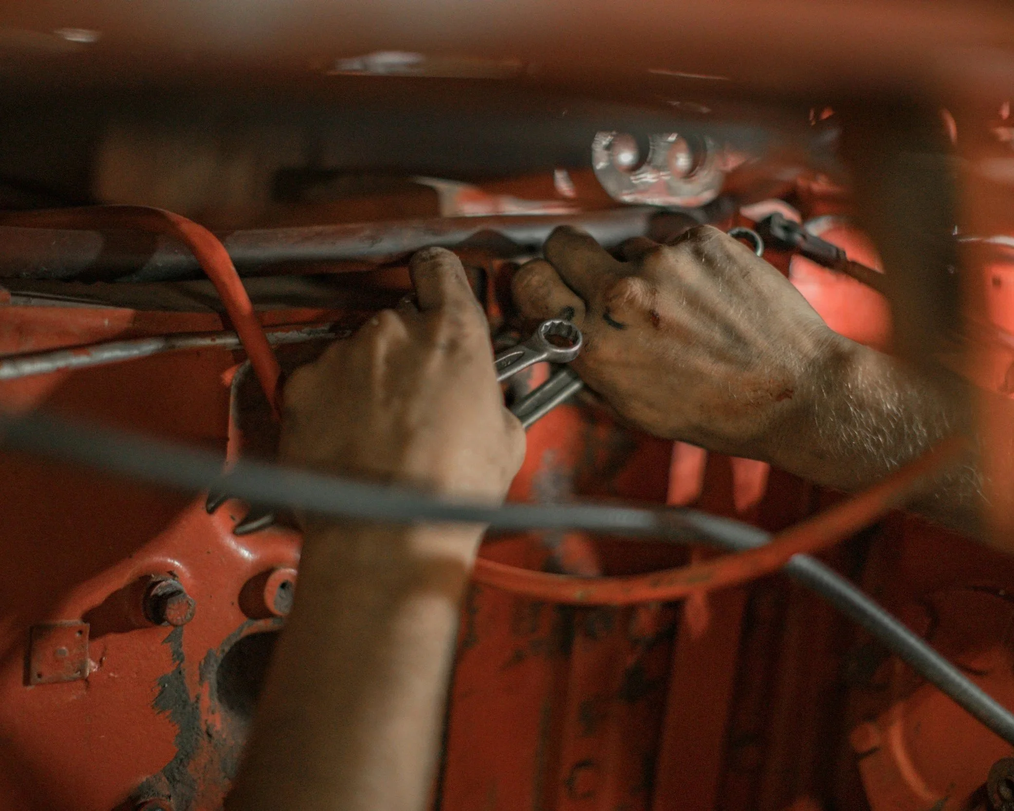 image shows a mechanics hands fixing brake lines in an engine bay