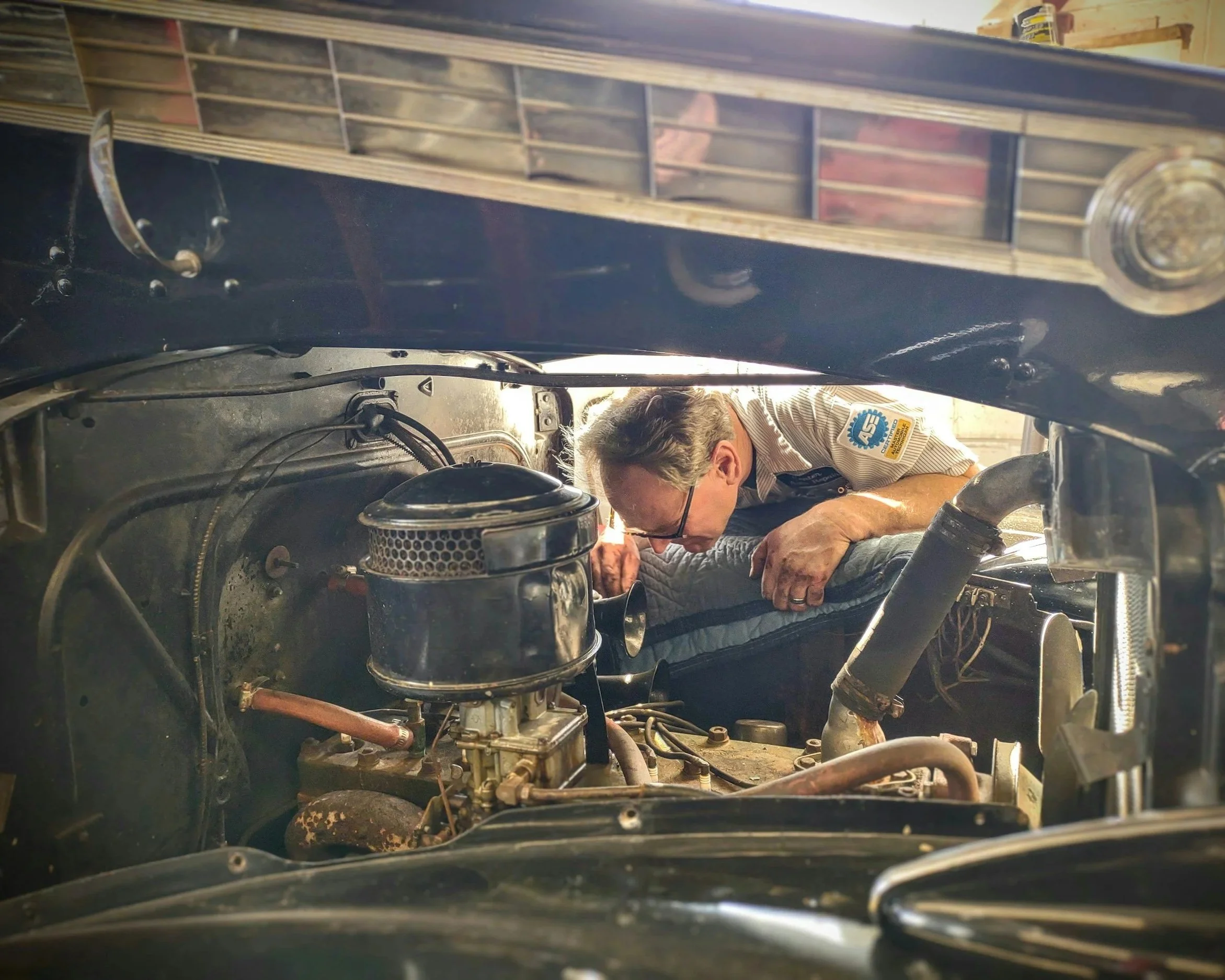 image shows a mechanic looking for an issue in an engine bay