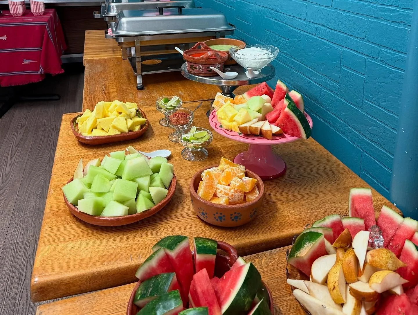 A colorful spread of fresh cut fruits including watermelon, cantaloupe, honeydew, and oranges on a wooden table.
