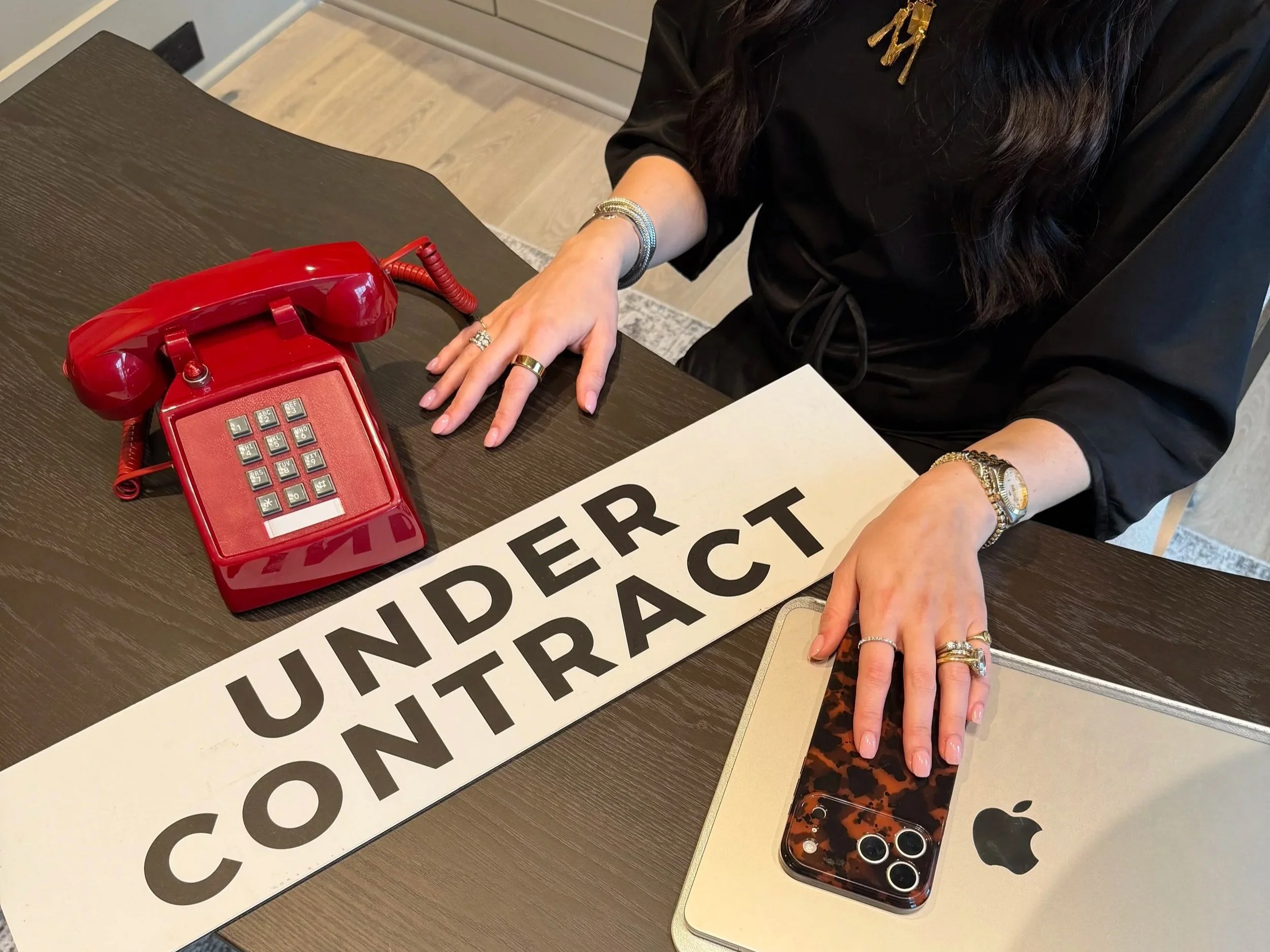 Real Estate Agent at work. Bird eyes view of desk with phone and sign that reads "Under Contract"