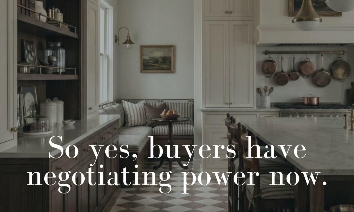 clean, classic and modern kitchen with open shelves, hanging pans and bench seating. Classic tile floors and granite countertops. Text overlay reads "so yes, buyers have negotiating power now"